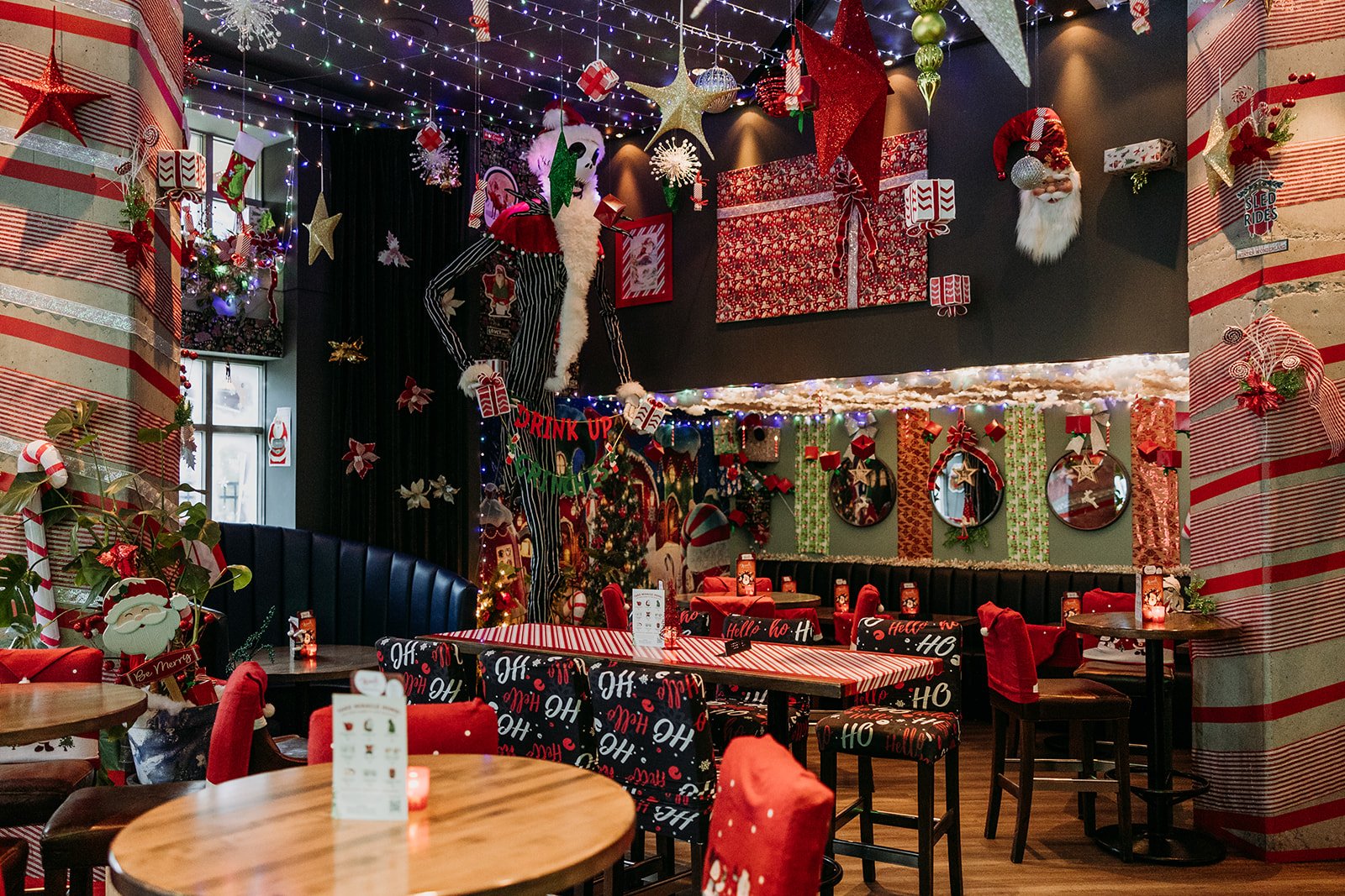 Christmas-themed restaurant decorated with lights, ornaments, and garlands, with tables and chairs covered in festive fabric at Miracle Pop Up Bar at The Raven Room in Whistler BC Canada.