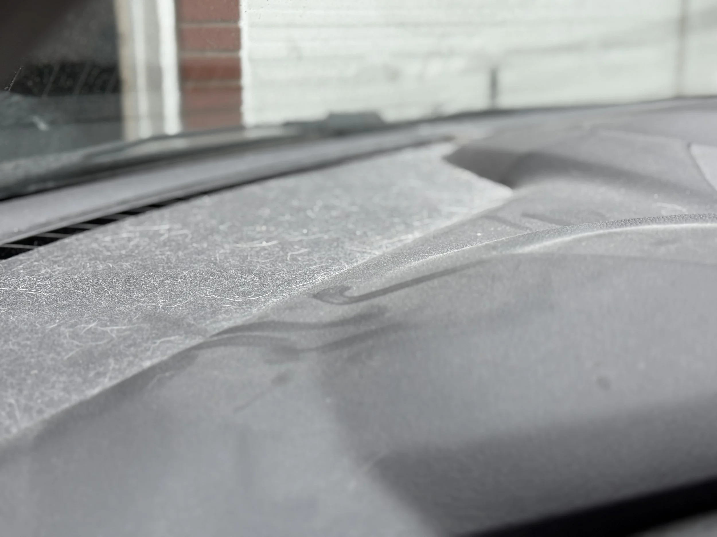Close-up of a dusty and scratched car dashboard with a windshield in the background.