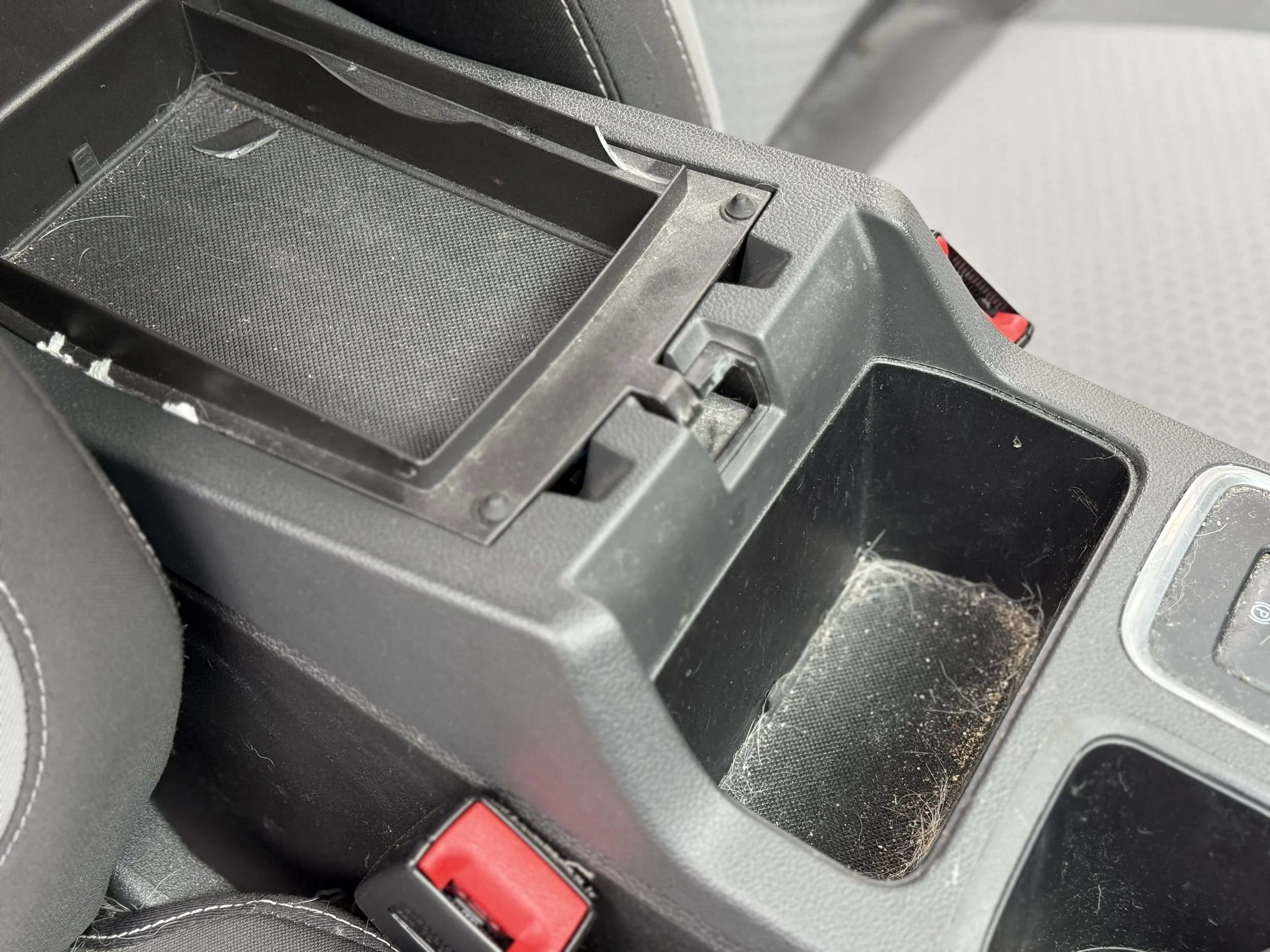Empty car center console with dirt and dust, with an open compartment on top.