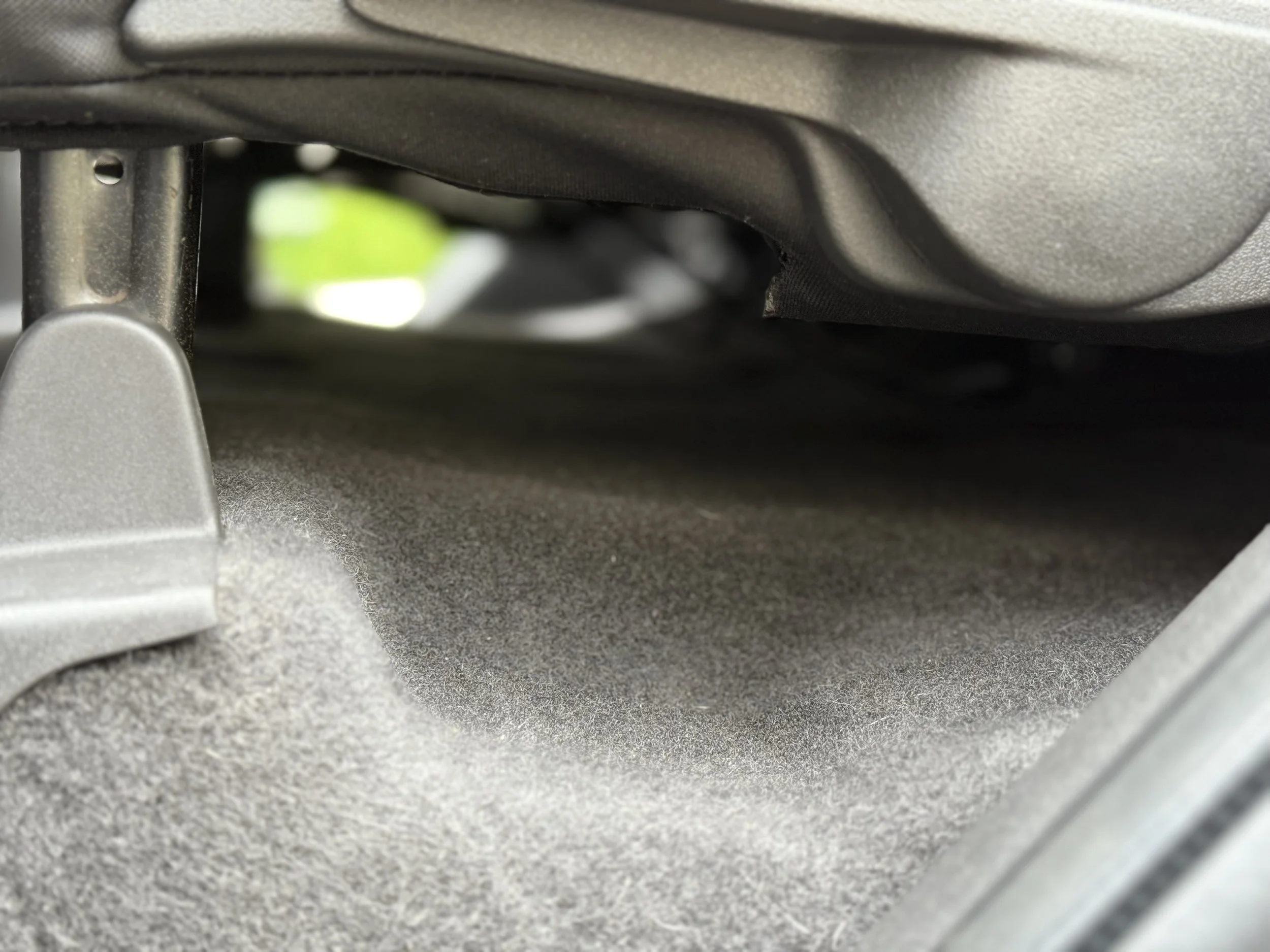 The interior of a car's glove compartment with soft gray lining and a blank storage space.