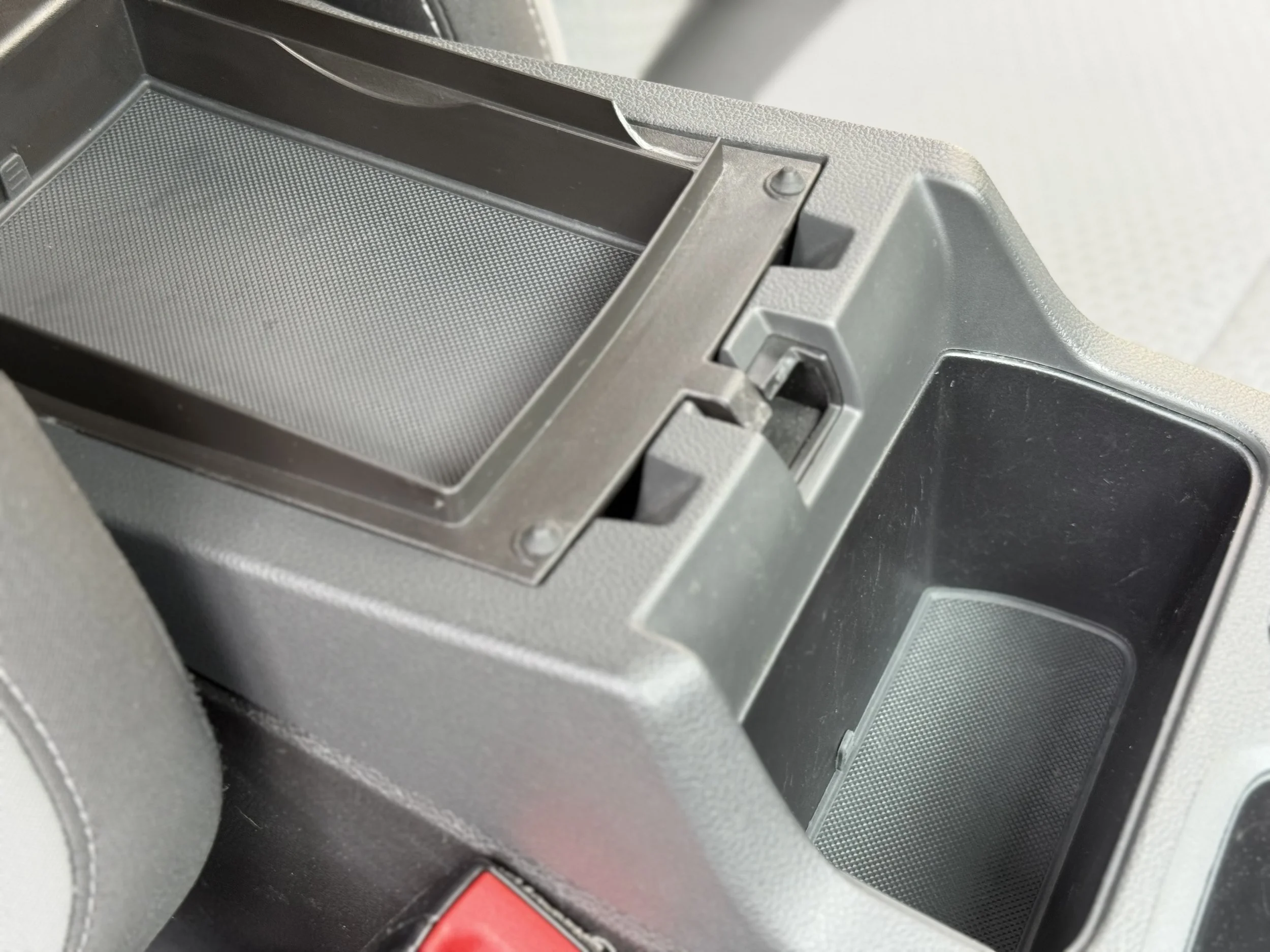 Close-up of a car's center console with an empty small compartment and a sliding tray above it.