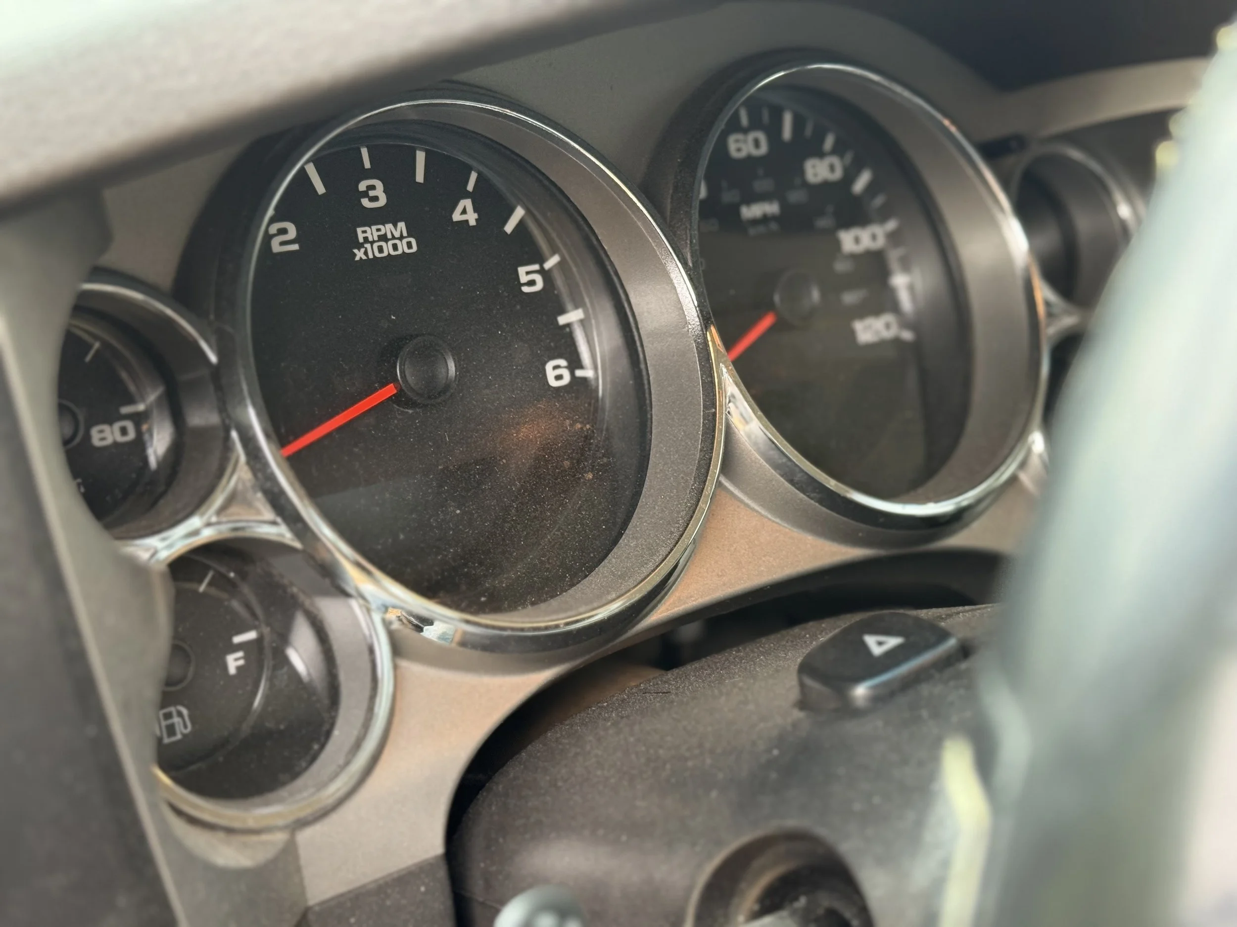 Close-up of a vehicle's dashboard showing a tachometer, speedometer, fuel gauge, and temperature gauge.