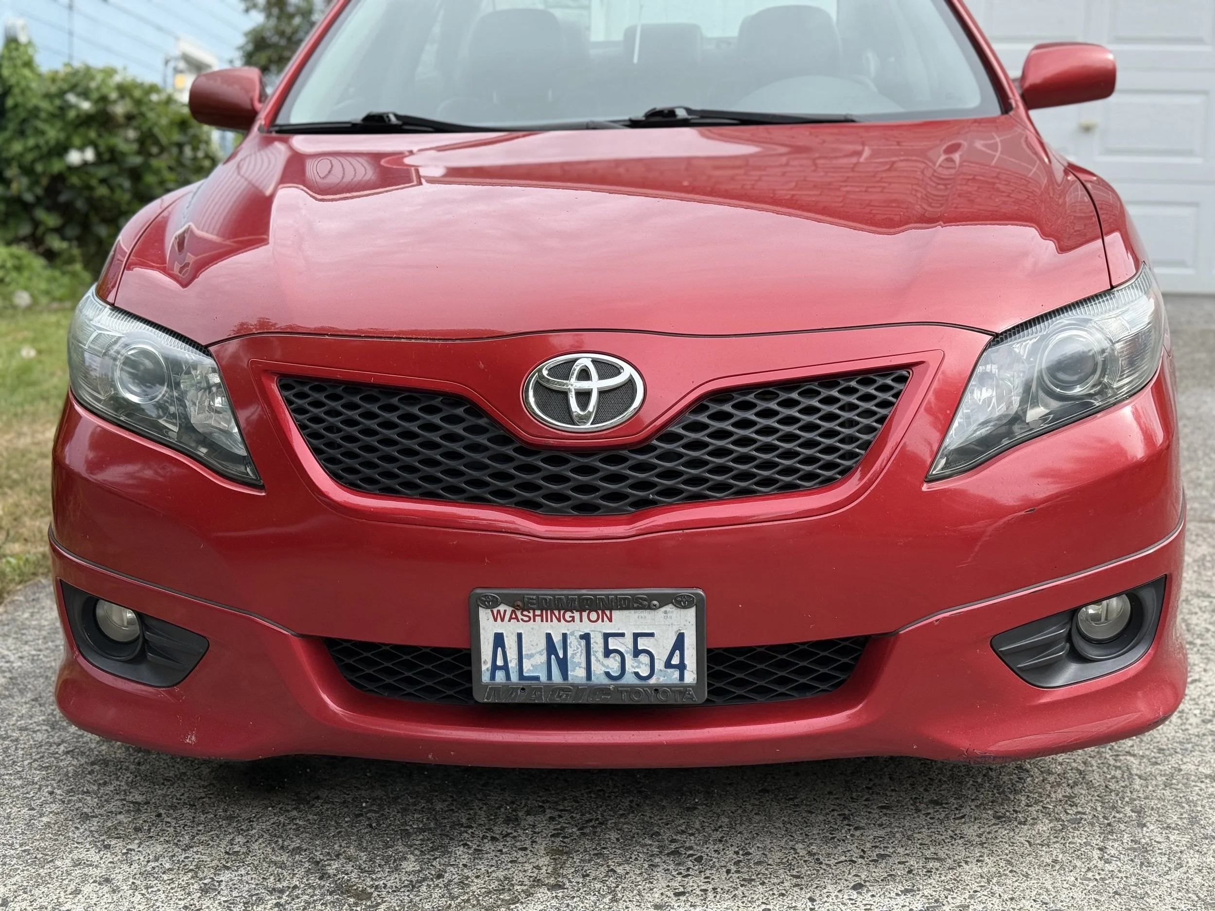 Front view of a red Toyota sedan with Washington license plate ALN1554 parked on driveway.