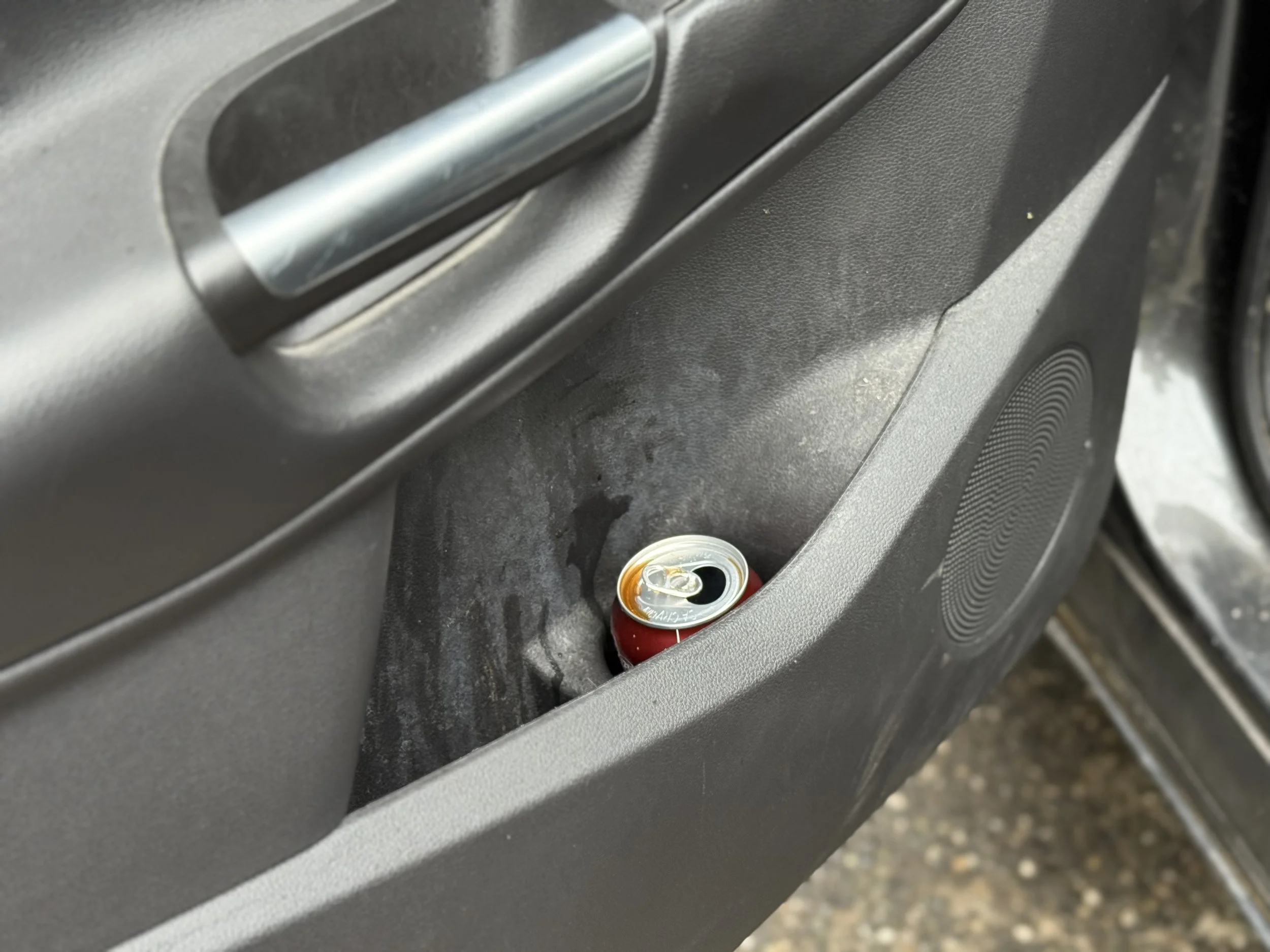 A can of soda inside a car door pocket.