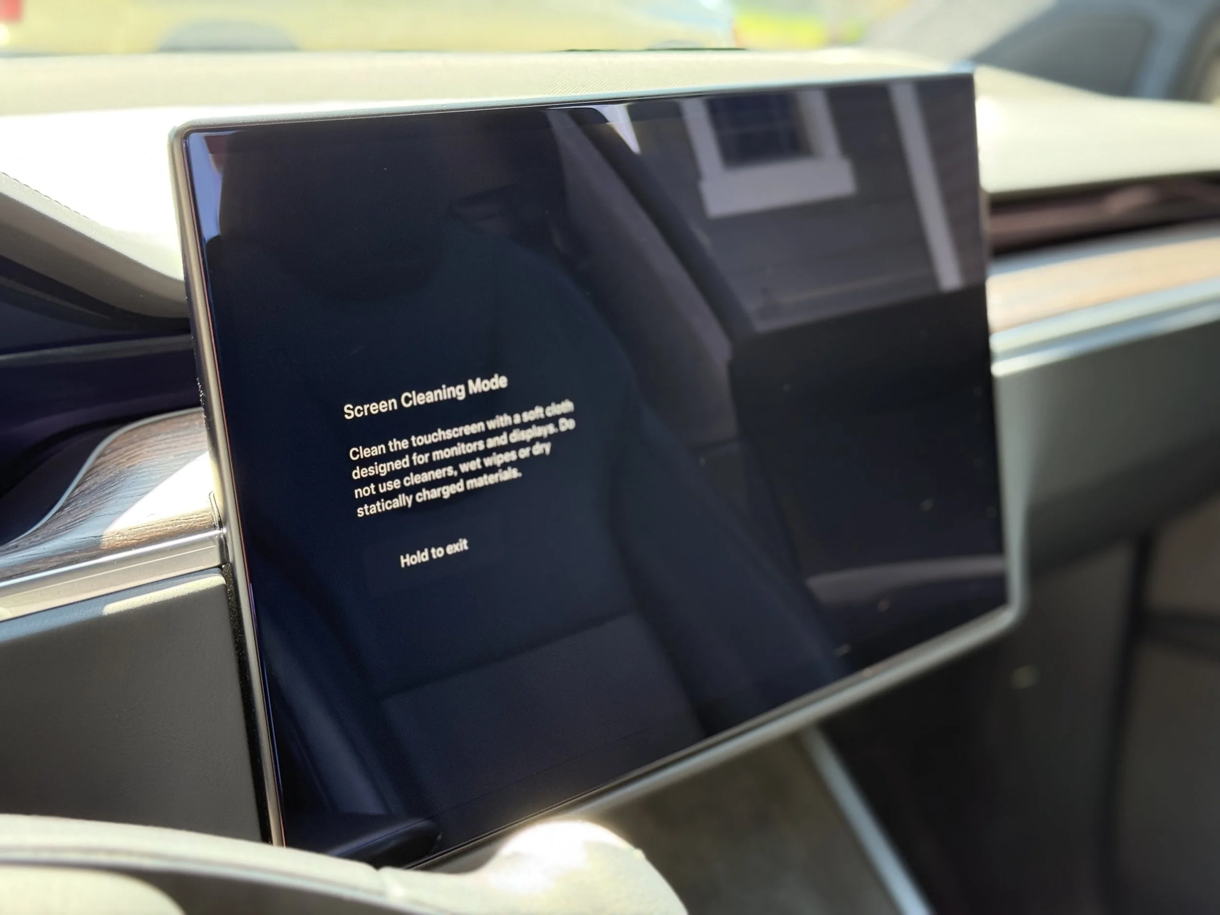 Tablet inside a vehicle displaying a screen cleaning mode message with instructions to clean the touchscreen with a soft cloth and avoid using cleaners or wet wipes.