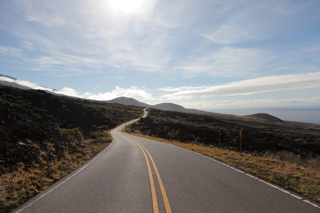 A winding road through a mountainous landscape under a partly cloudy sky.