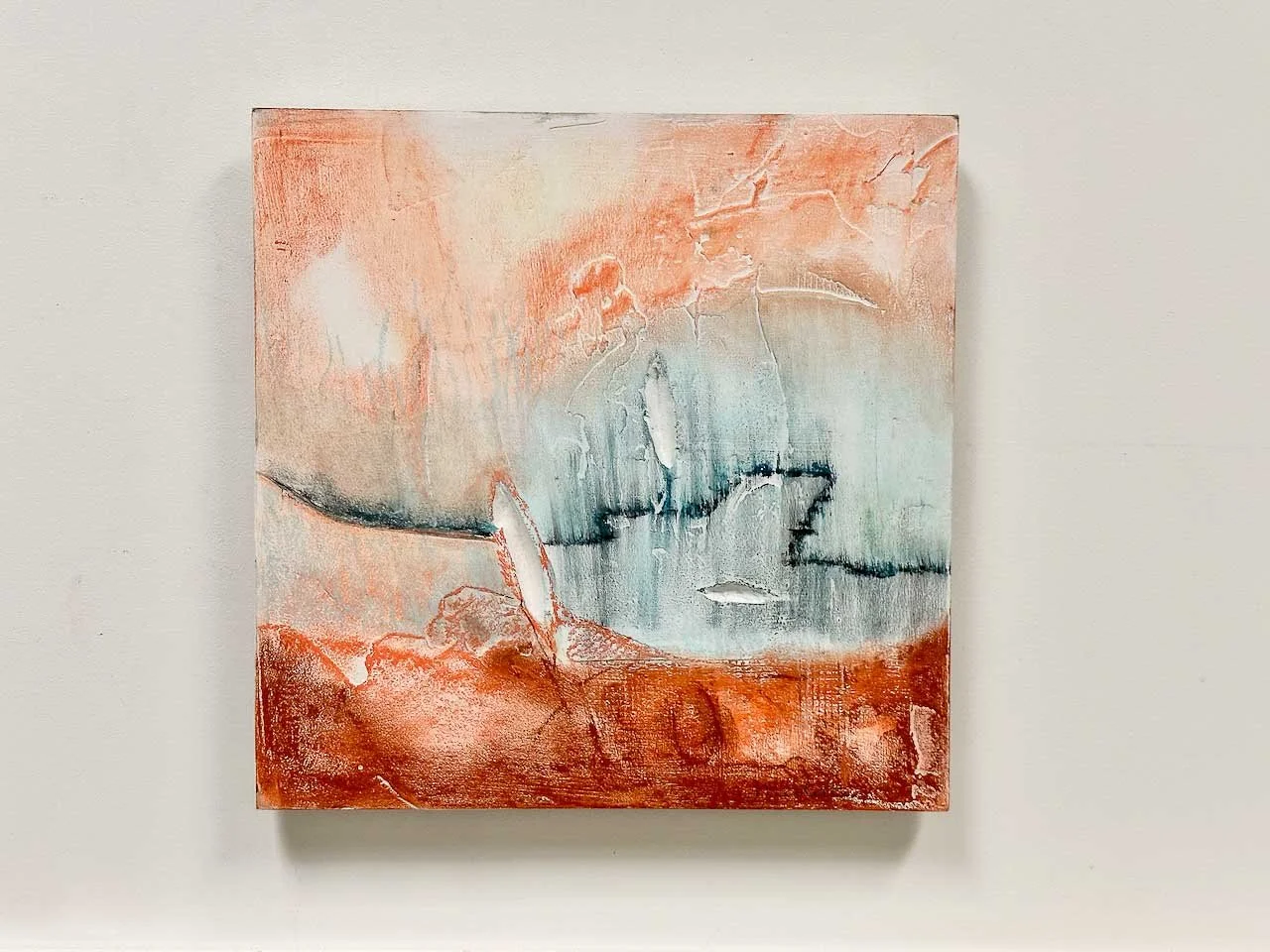 Abstract painting with earthy tones of orange and blue, featuring textured elements on a canvas.