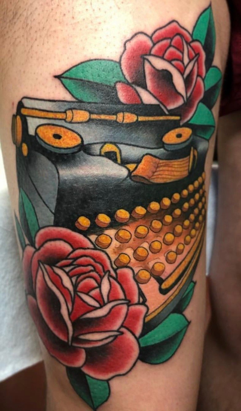 Tattoo of a vintage phonograph with pink roses and green leaves surrounding it.