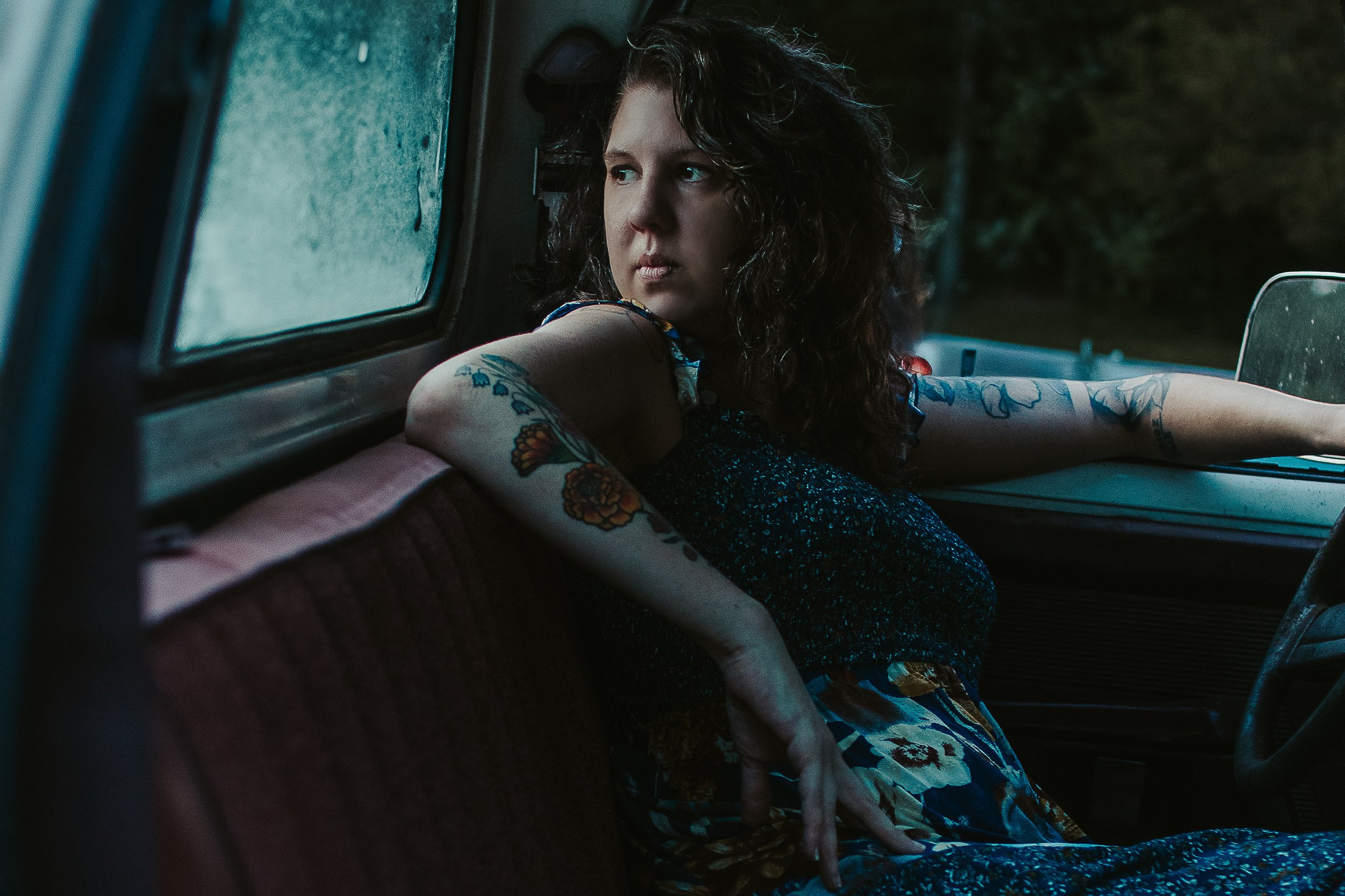 Dramatic portrait of woman in car with low light and moody setting.