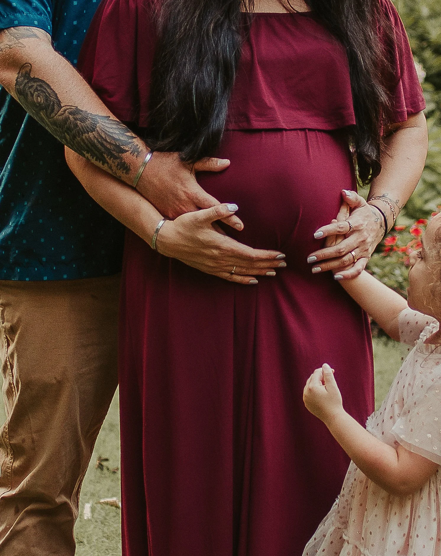 Family maternity session showing baby bump held by husband and daughter
