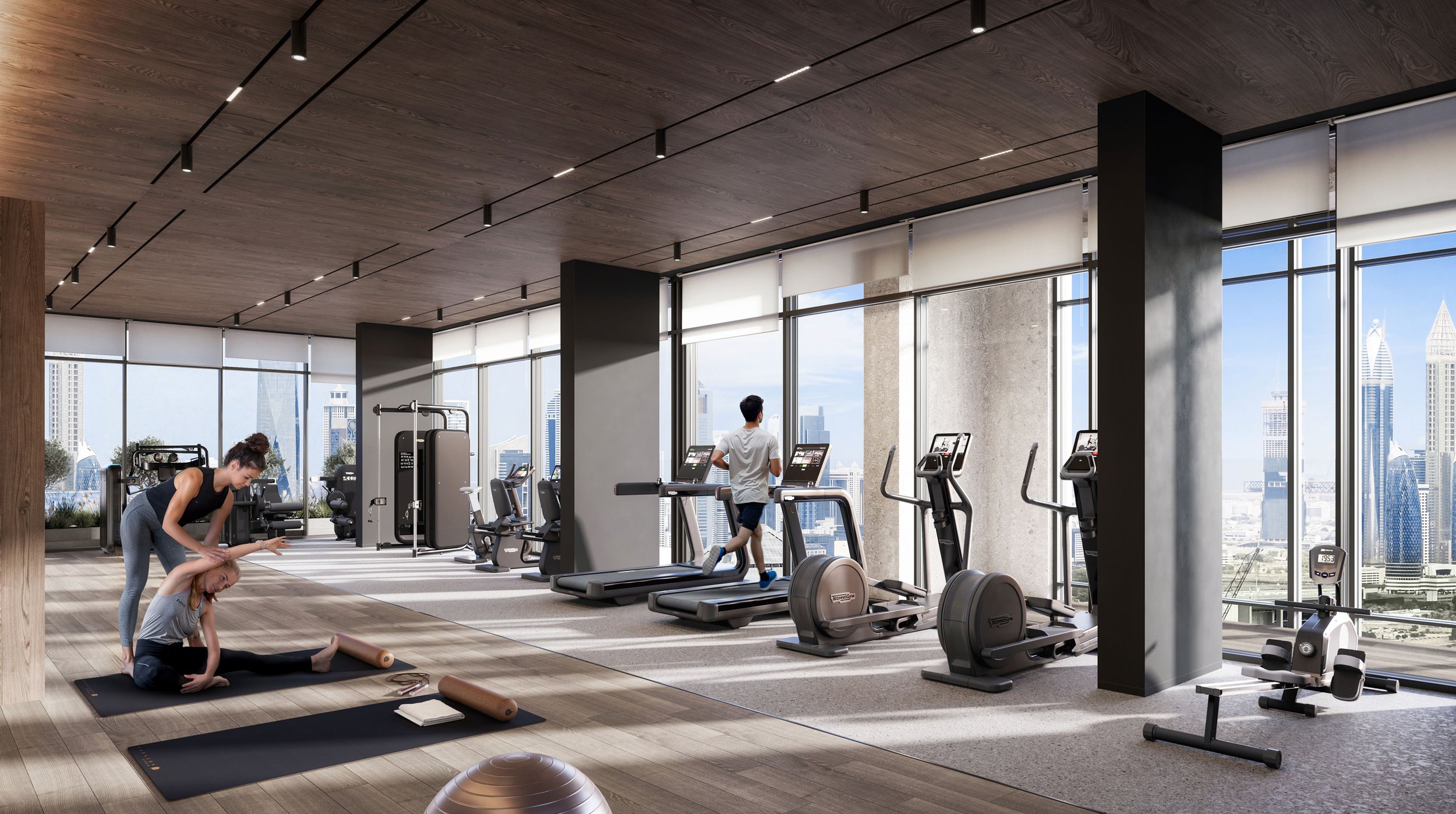 Modern gym with large windows showing city skyline, featuring workout equipment like treadmills, elliptical machines, and a yoga area with a woman stretching.
