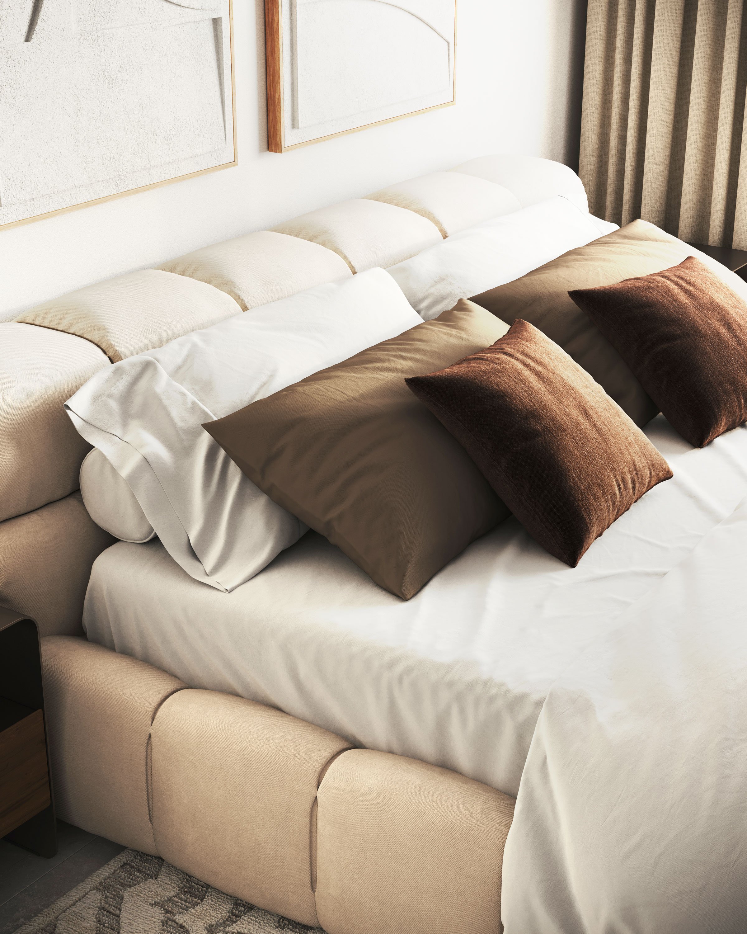 A neatly made bed with beige headboard, topped with white and brown pillows, and beige silky bedsheets, in a modern bedroom with framed artwork and beige curtains.