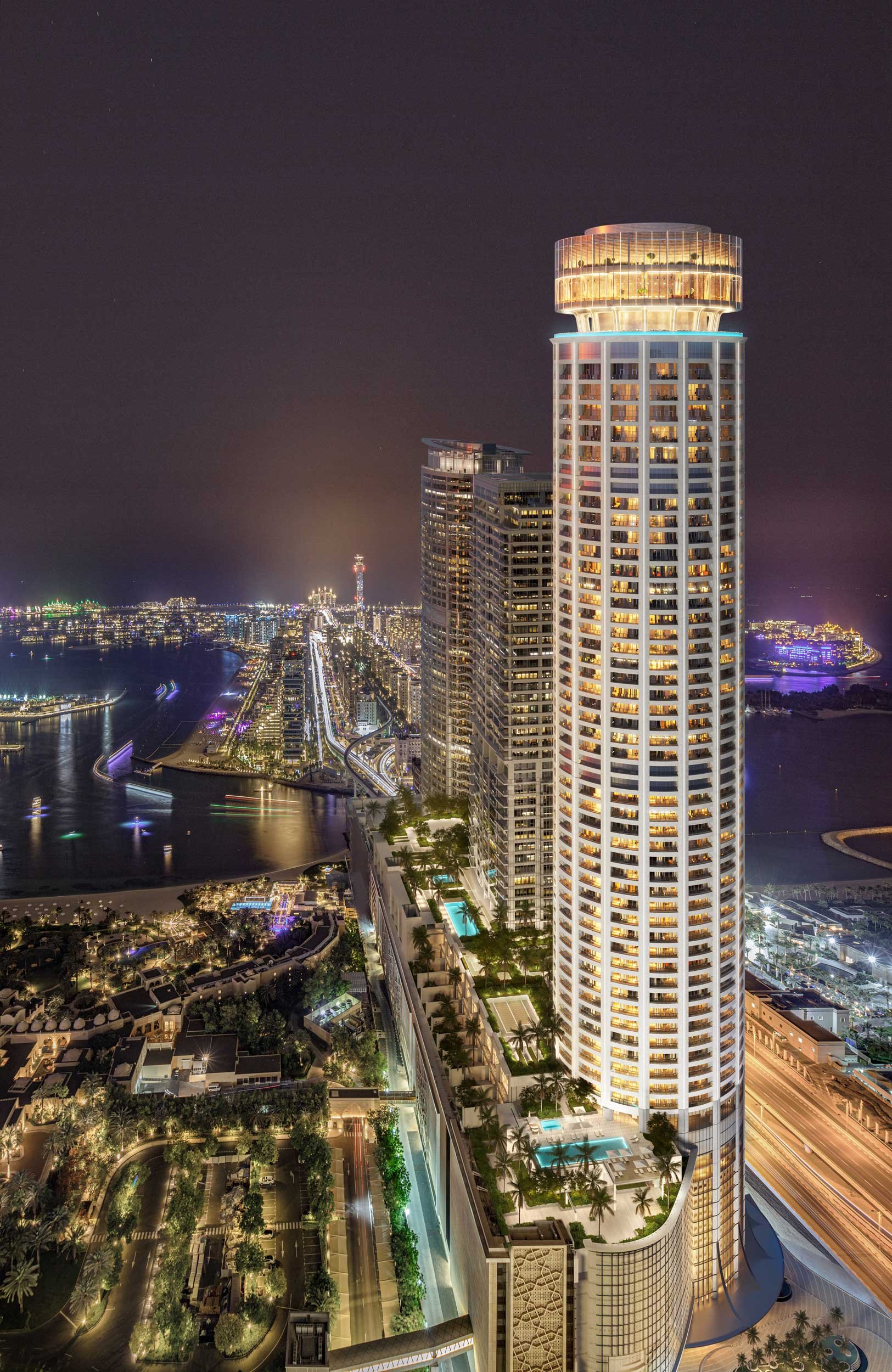 Tall, illuminated skyscraper at night in a bustling city with bridges and water nearby, city lights reflecting on Palm Dubai.  Nakheel. Dubai Holding CGI. Dubai Real estate marketing.