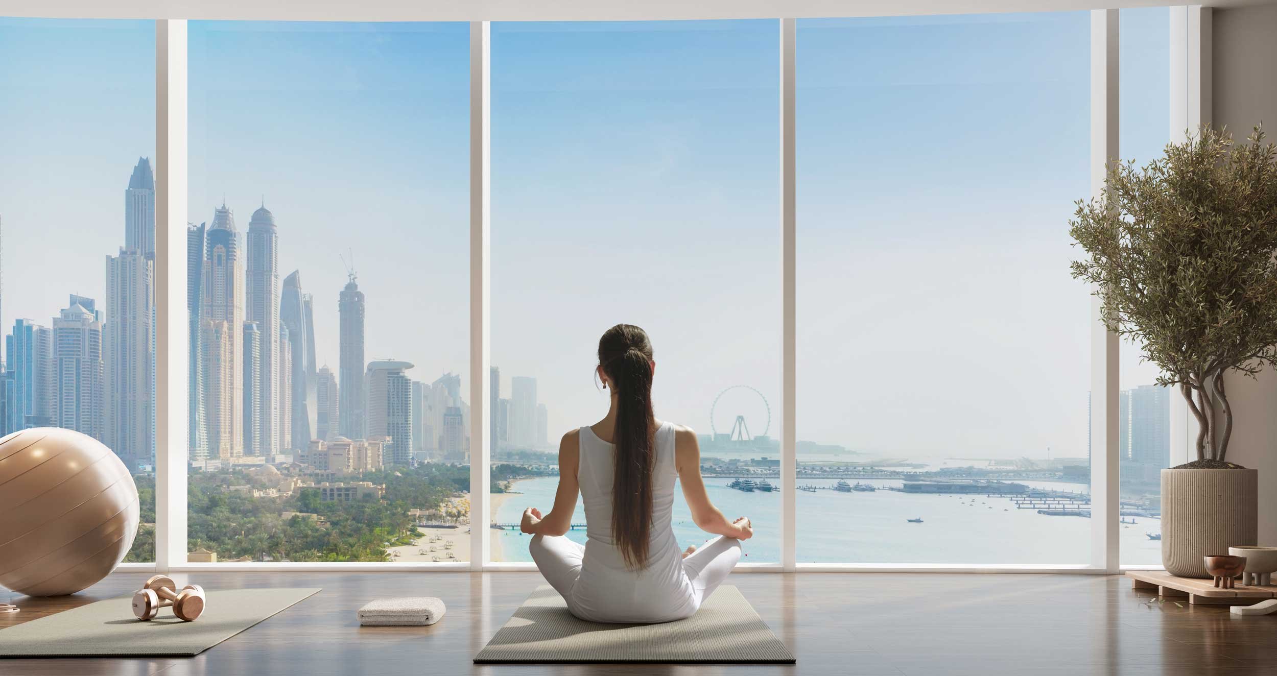 A woman practicing yoga or meditation in a bright room with large floor-to-ceiling window. The room has a yoga mat, exercise ball, dumbbells, and indoor plants. Nakheel. Dubai Holding CGI. Dubai Real estate marketing.