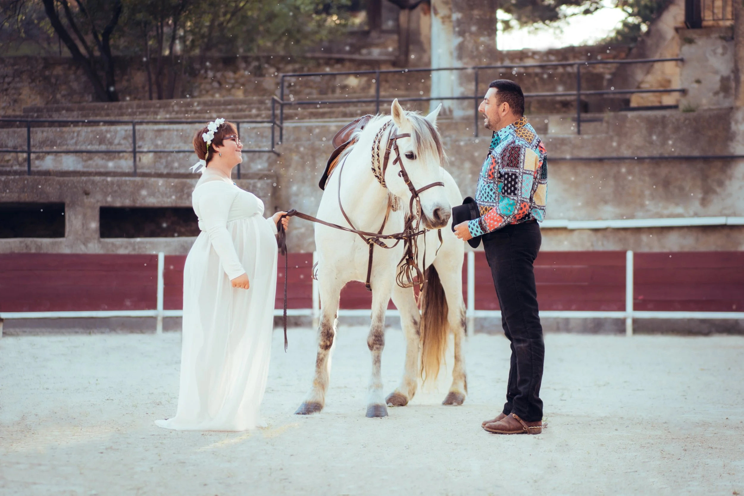 Deux personnes debout avec un cheval blanc entre elles.