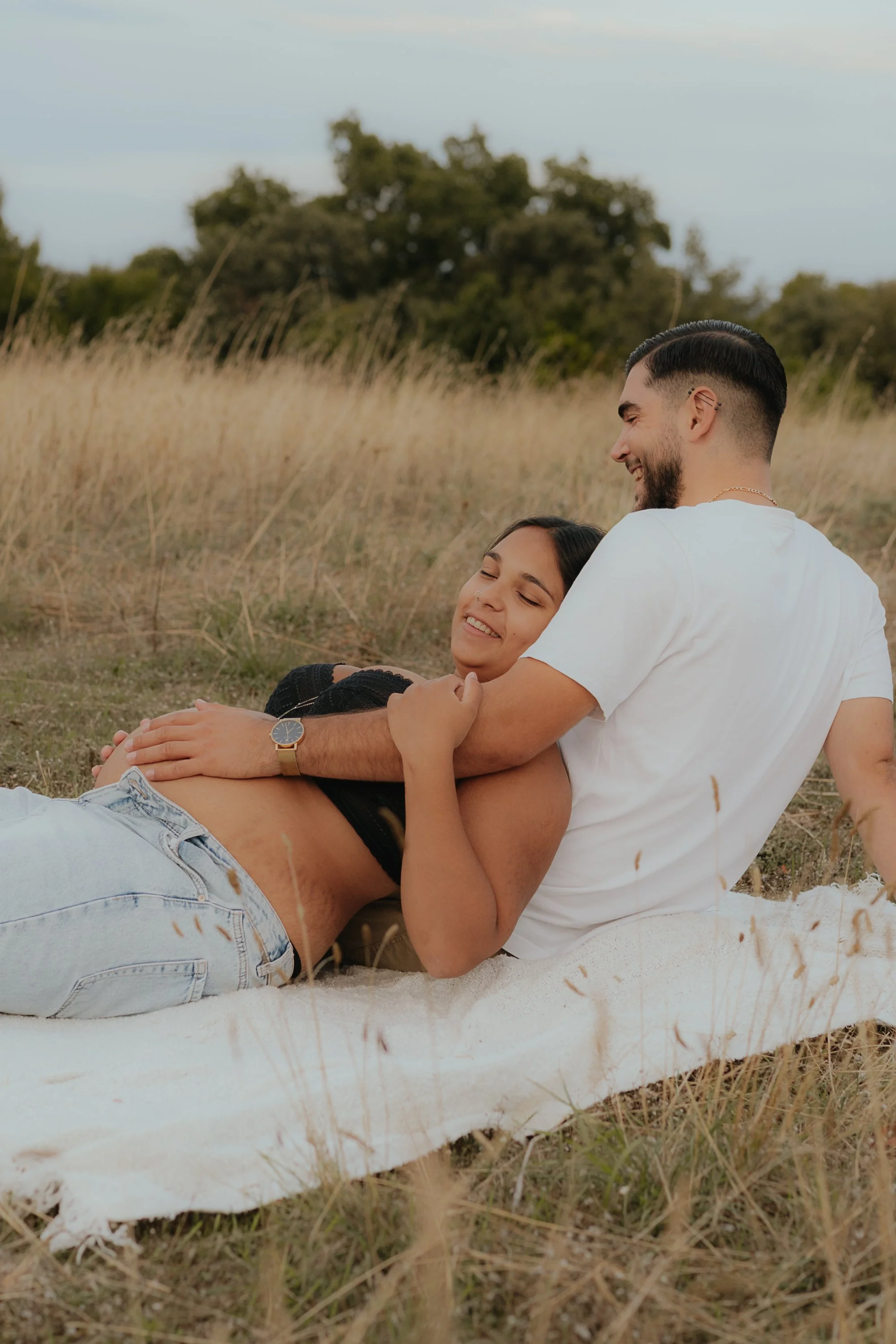 SÉANCE GROSSESSE SALON DE PROVENCE FEMME ALLONGER ENCEINTE SUR LE SOL DANS UN PRÈS AVEC LE FUTUR PAPA