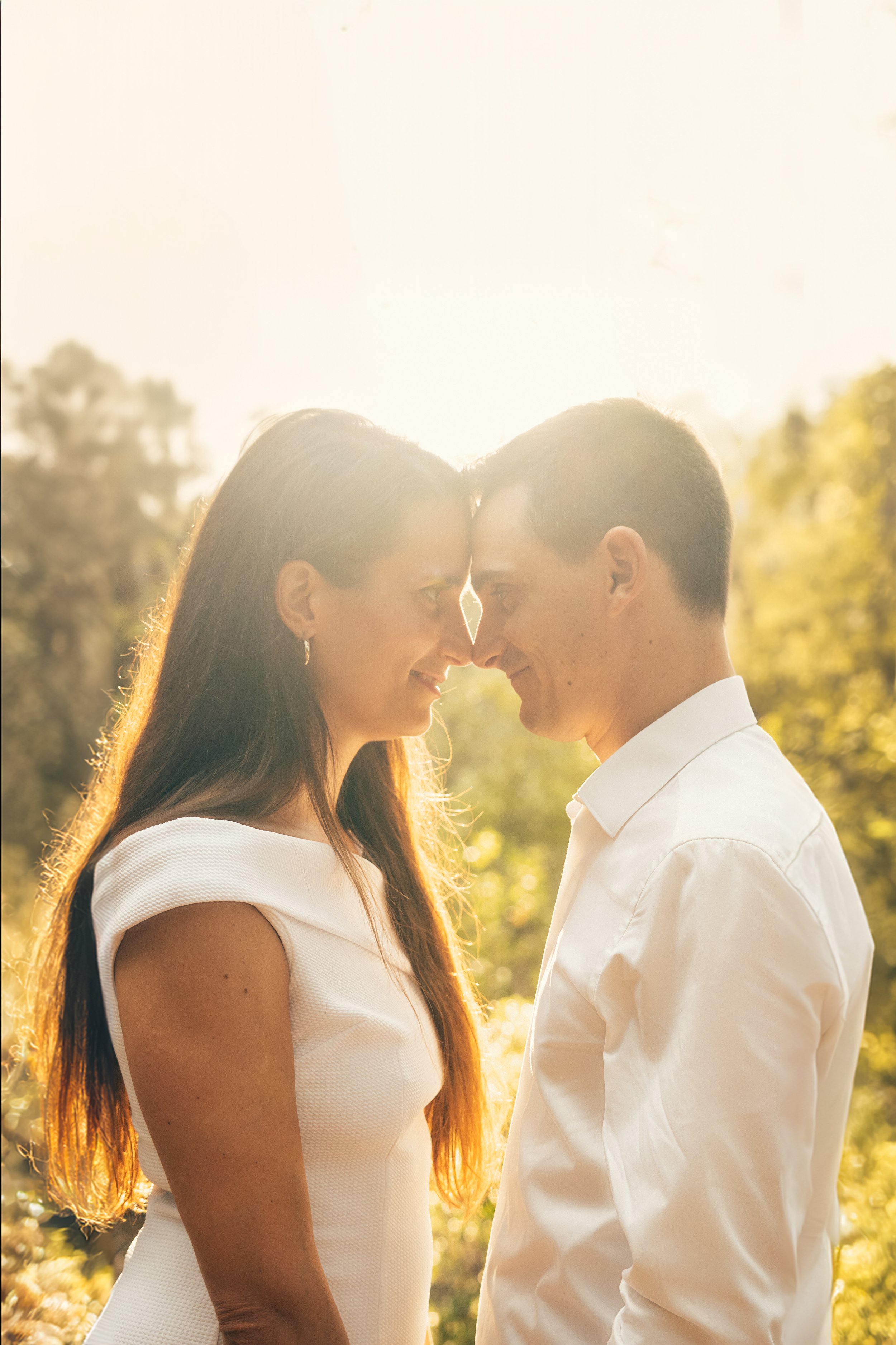 Un homme et une femme se font face avec affection lors d'une belle journée ensoleillée, entourés de verdure.