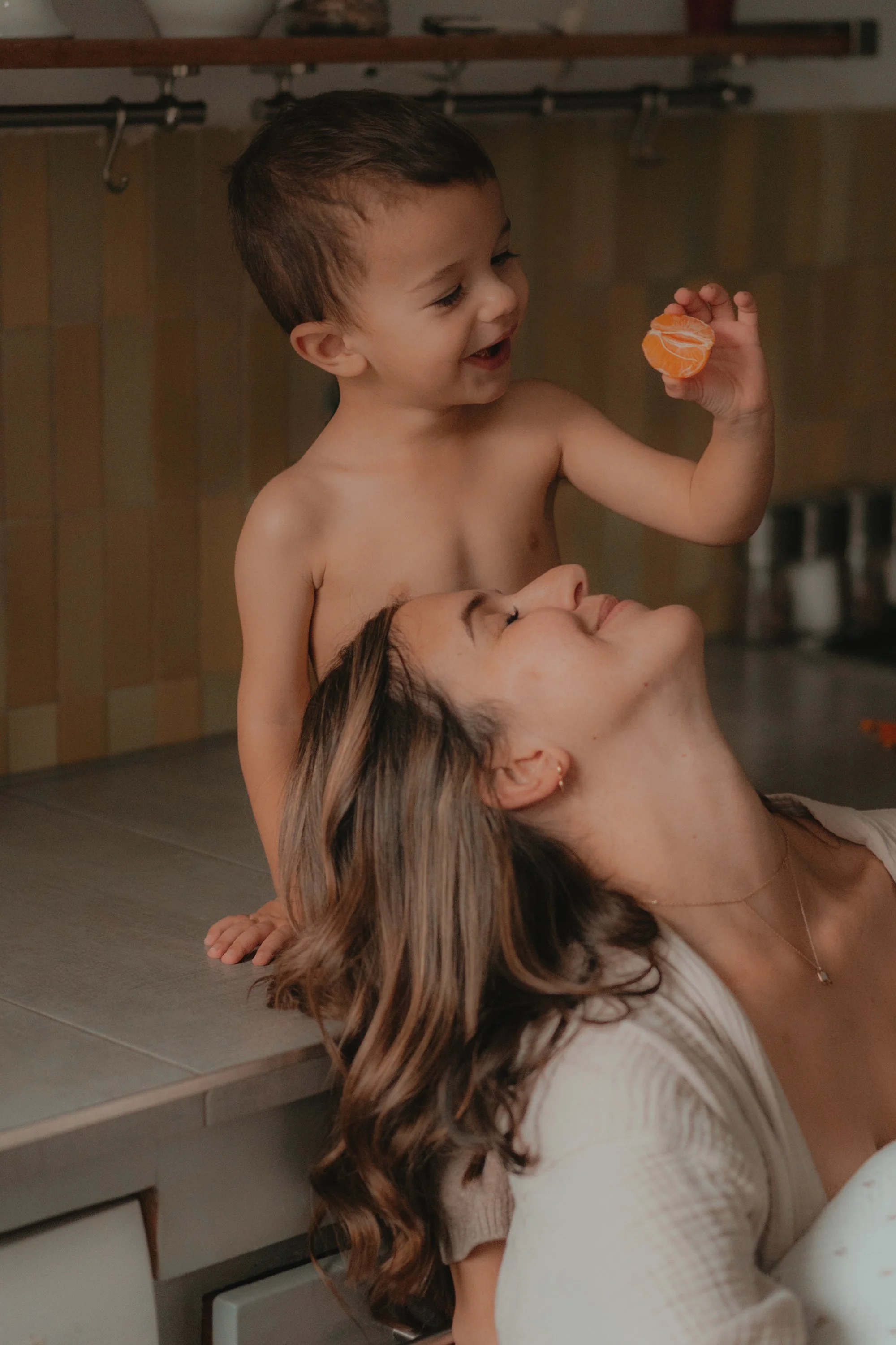 SÉANCE FAMILLE - ENFANT 4 ANS QUI JOUE AVEC SA MAMAN QUI SOURIT
