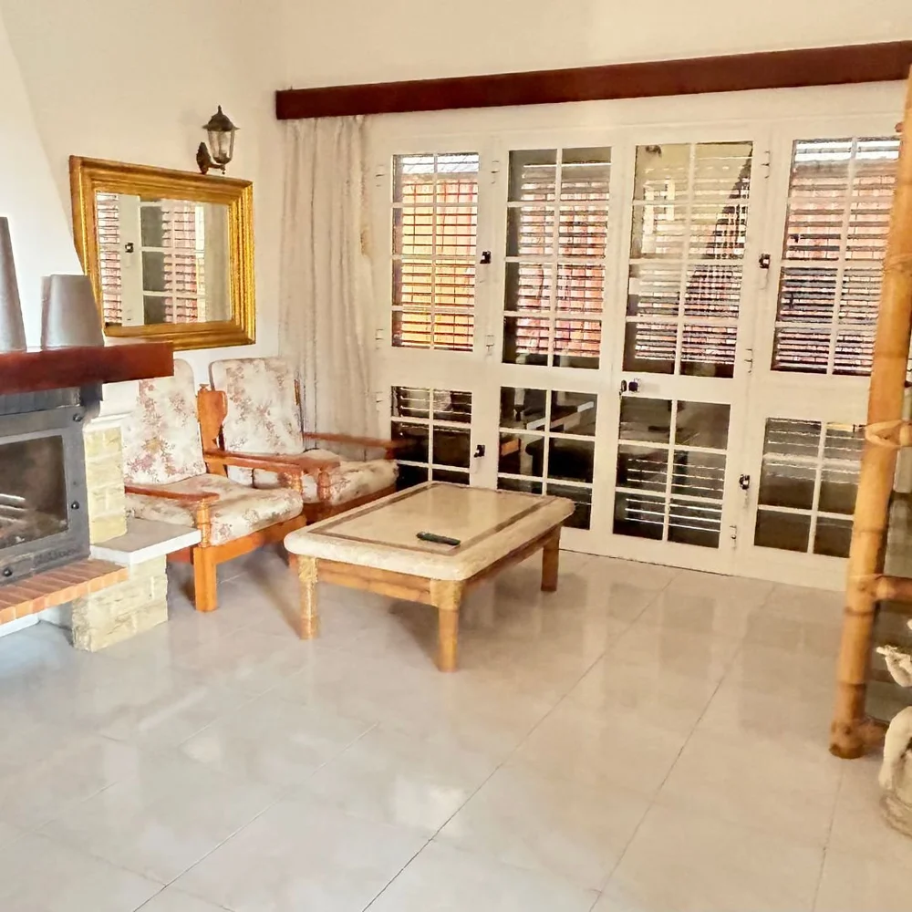 A sitting room with an open fireplace and shuttered glazed doors