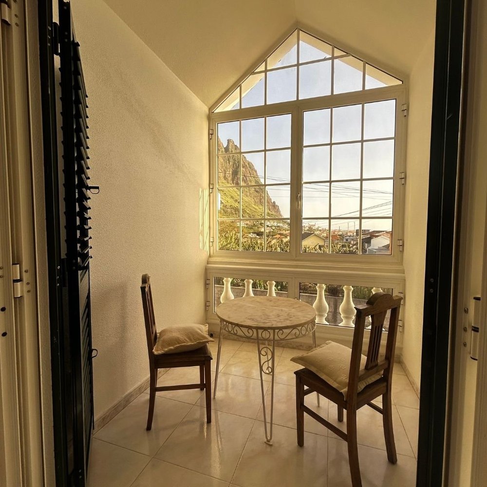 A gable window at the top of the house with a table and two chairs