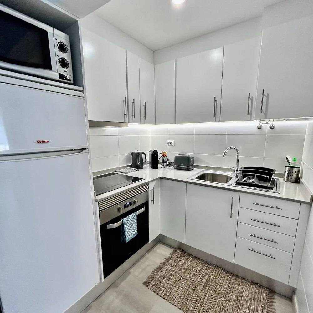 White fitted kitchen with an oven under an induction hob