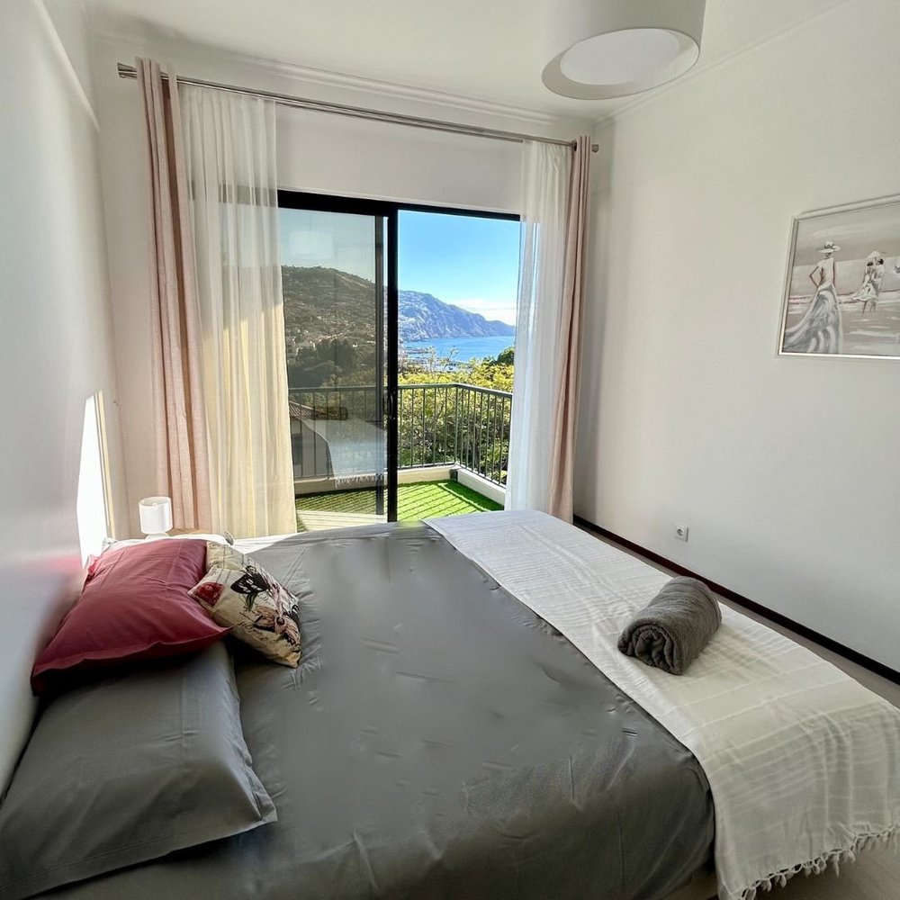 Main bedroom with a wide bed and curtained sliding doors