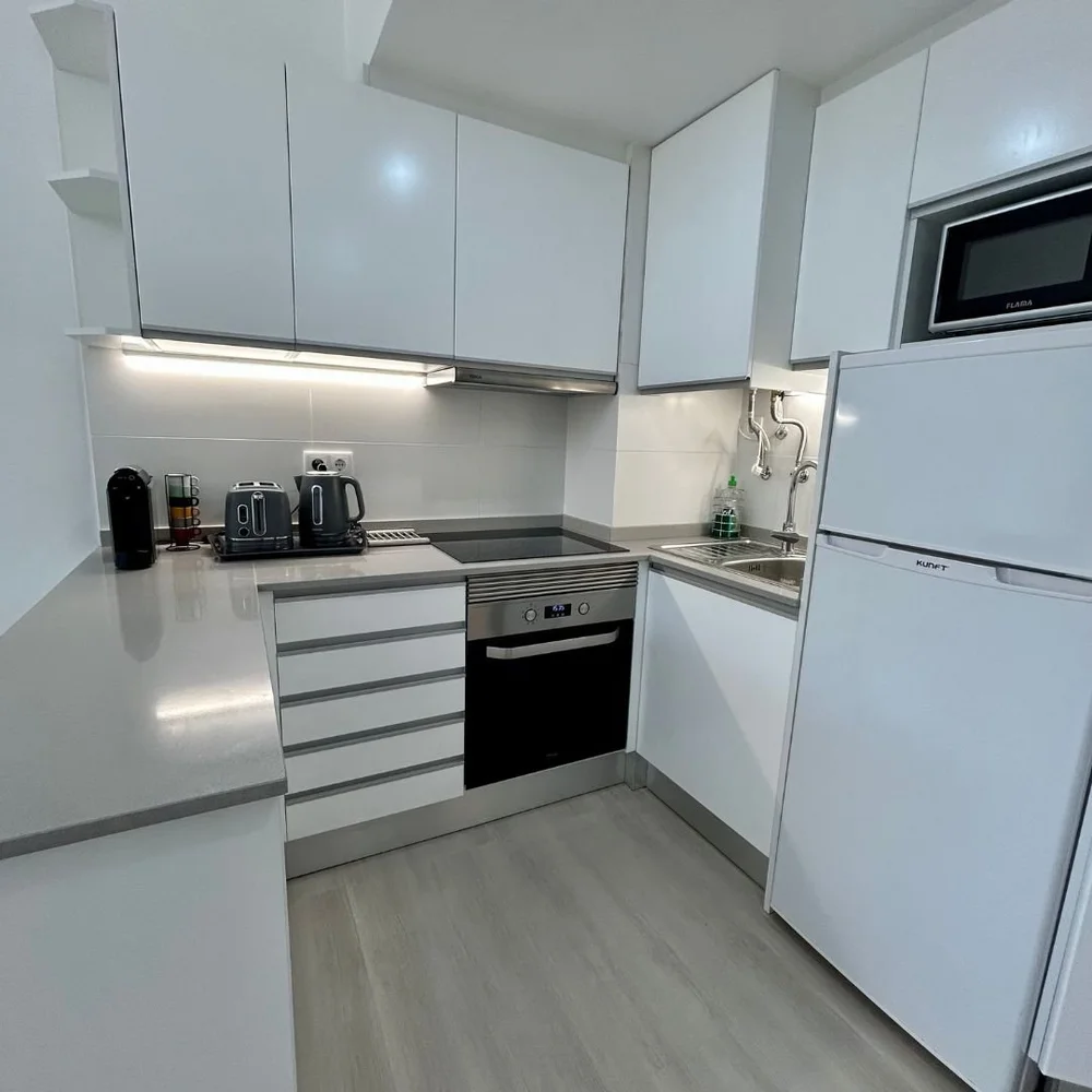 White fitted kitchen with an oven under an induction hob