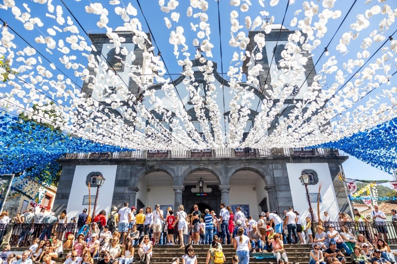 Garlands of white and blue paper flowers strung above the crowded steps of the Monte church during the festa.