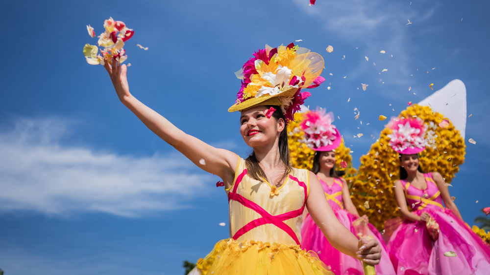 Dancers in flower-covered hats and bright dresses at the Madeira Flower Festival parade
