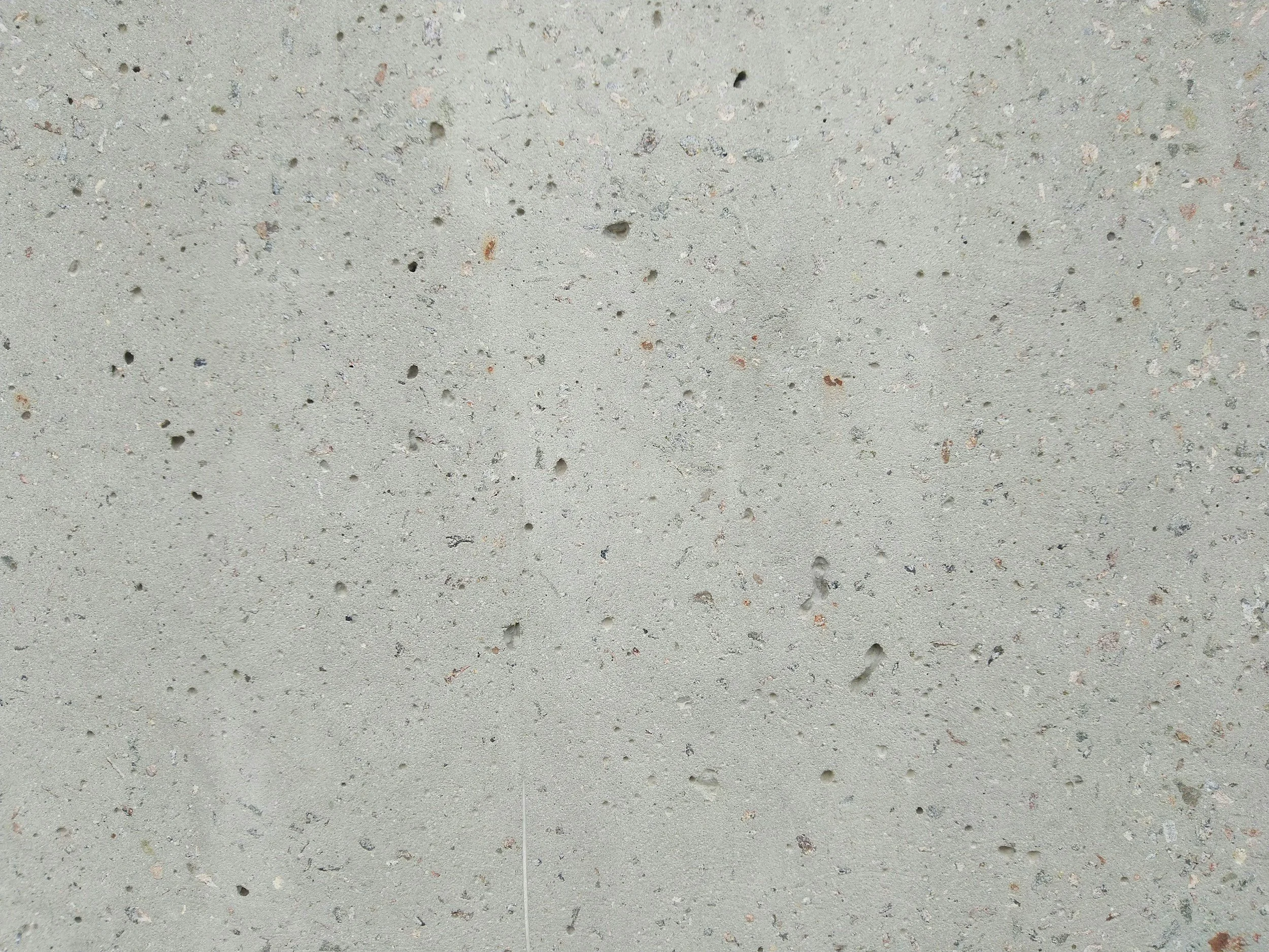 Close-up of a concrete surface with small pebbles and irregularities.