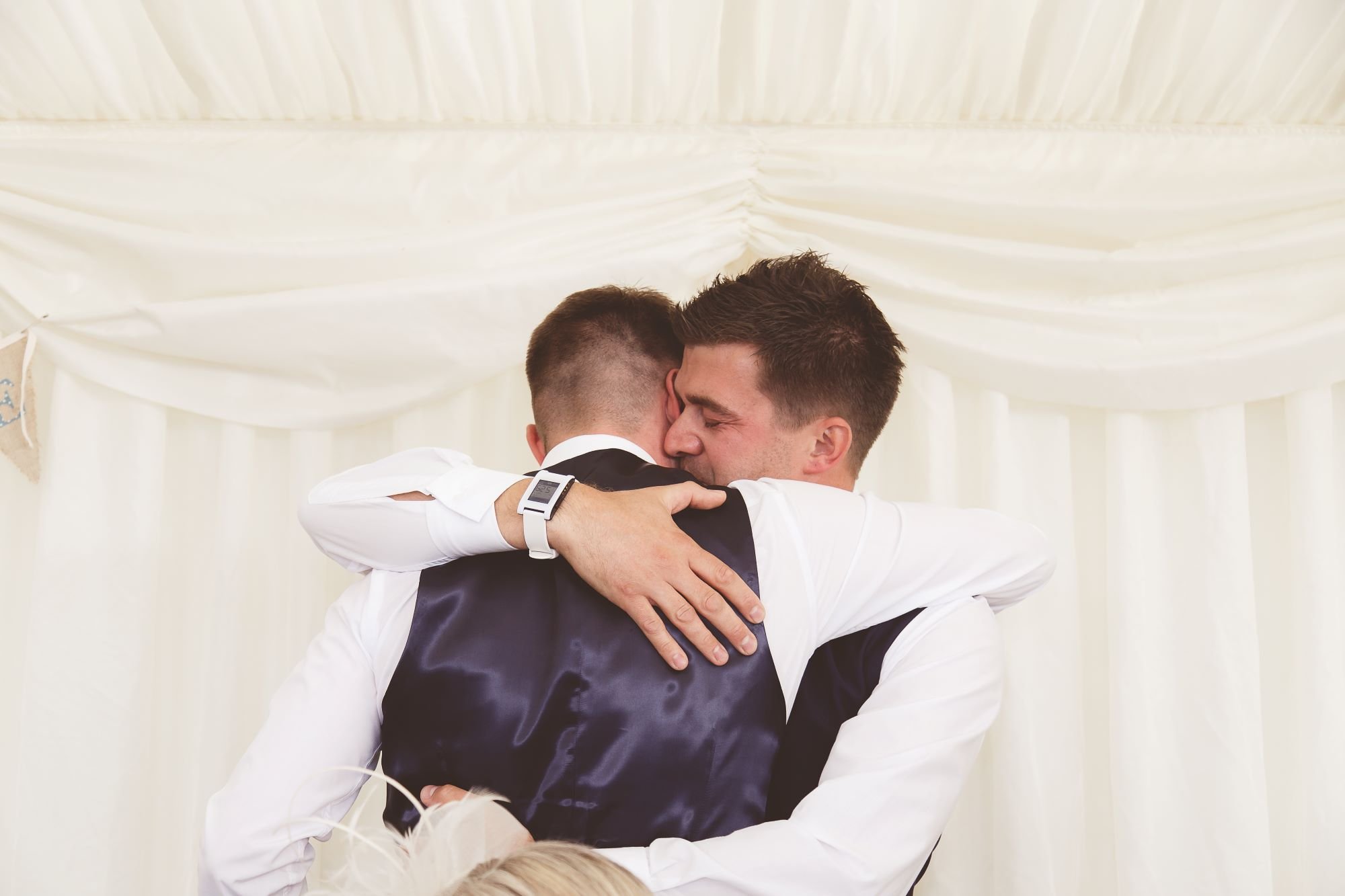 Groom and best man hugging during wedding celebrations
