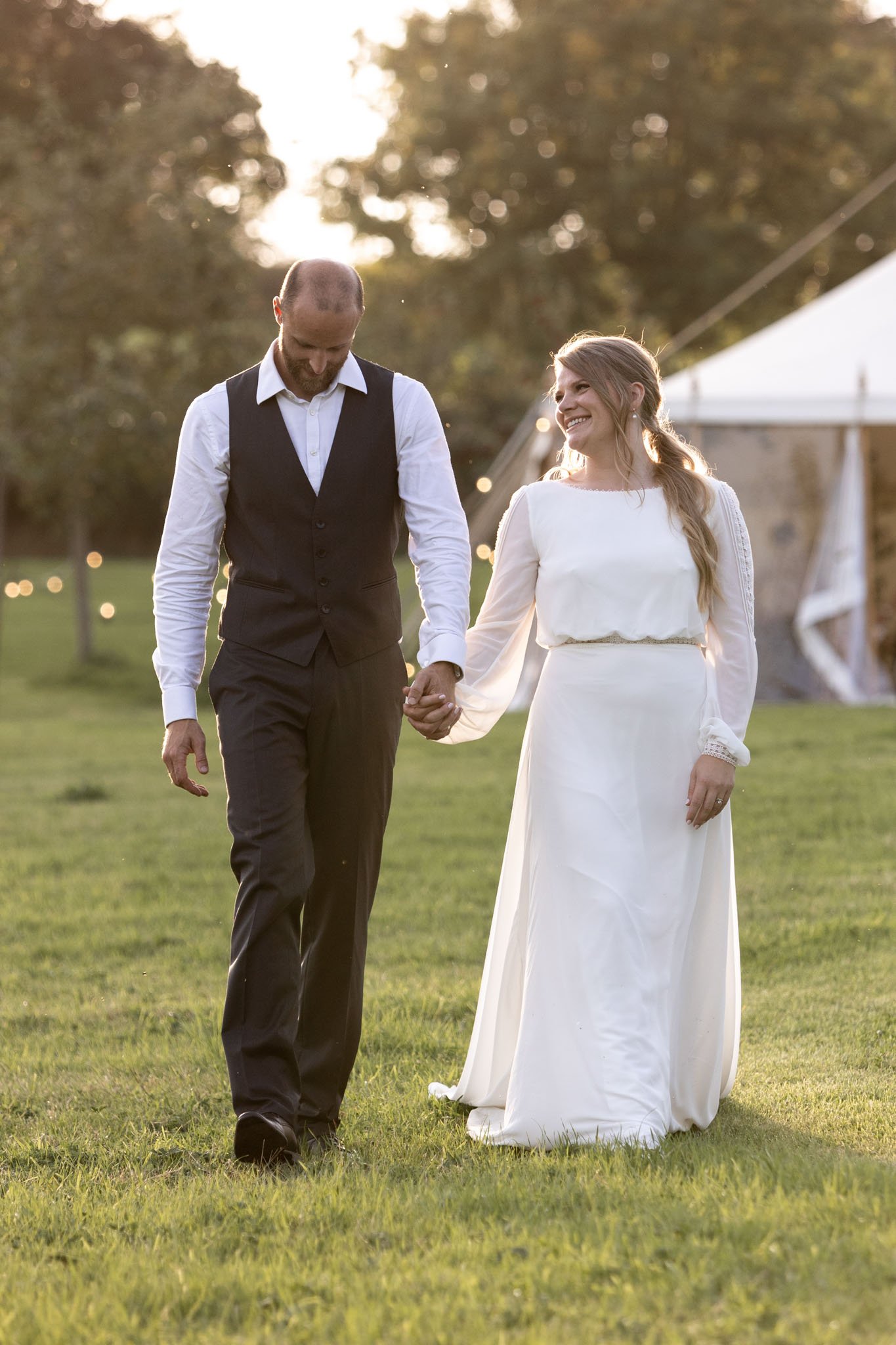 Bride and Groom walking in a field during golden hour on their wedding day
