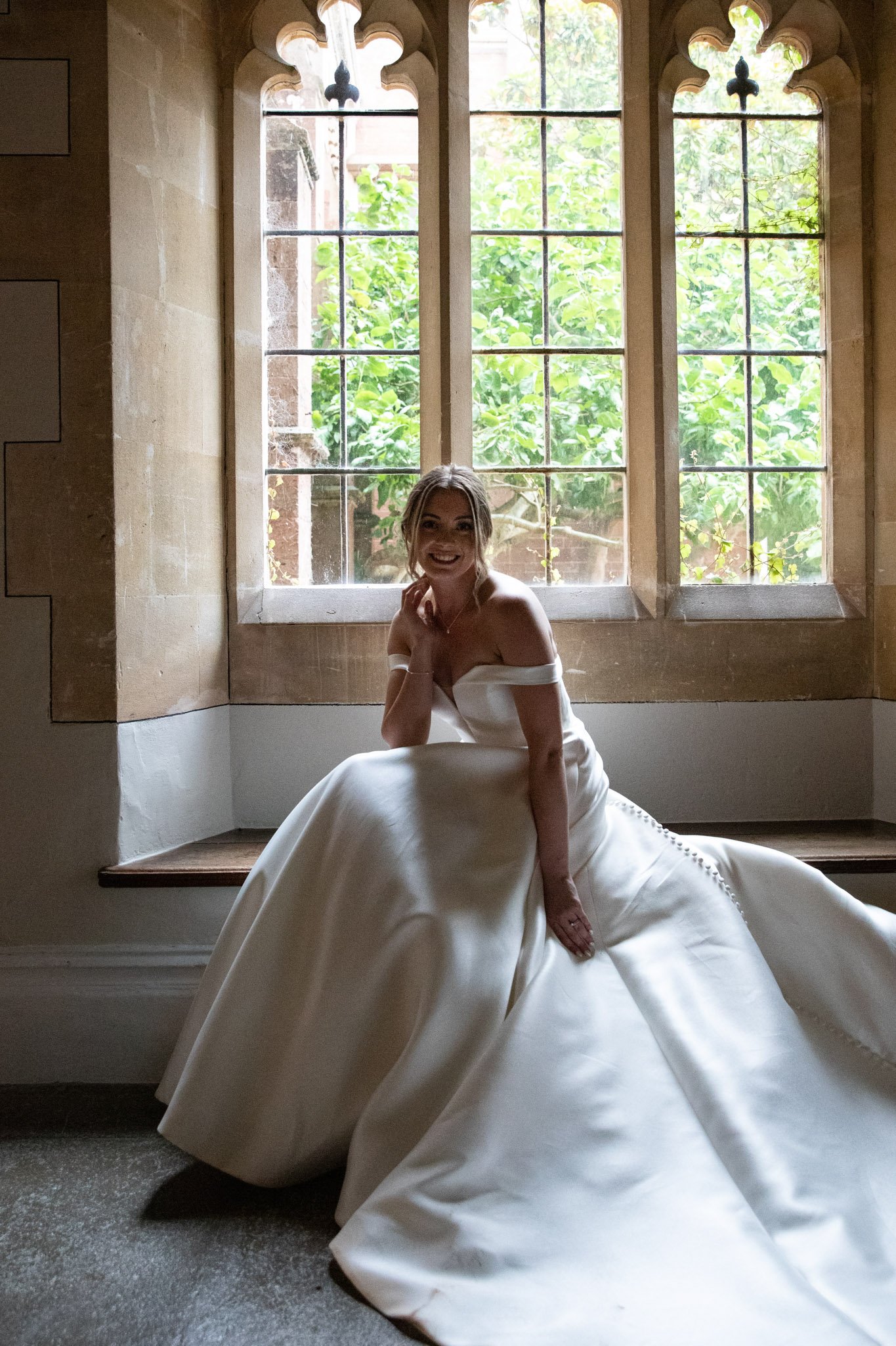bride posing for photos at St Audries Park in window, smiling at the camera