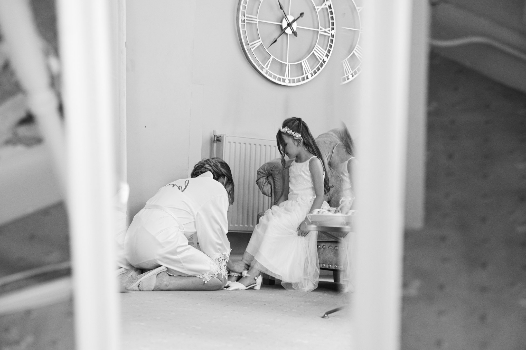 Bride putting flower girl's shoes on