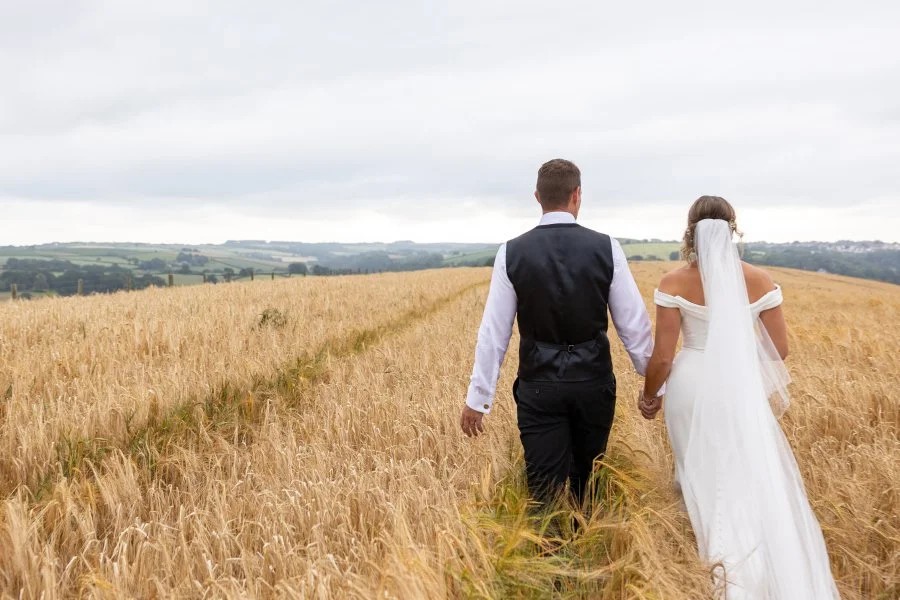 Bride and Groom walking hand in hand in a corn field