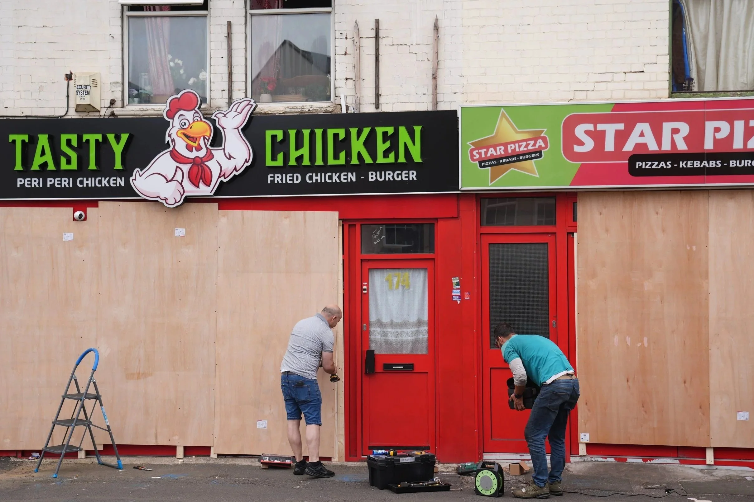 Two workers outside shops under going renovation