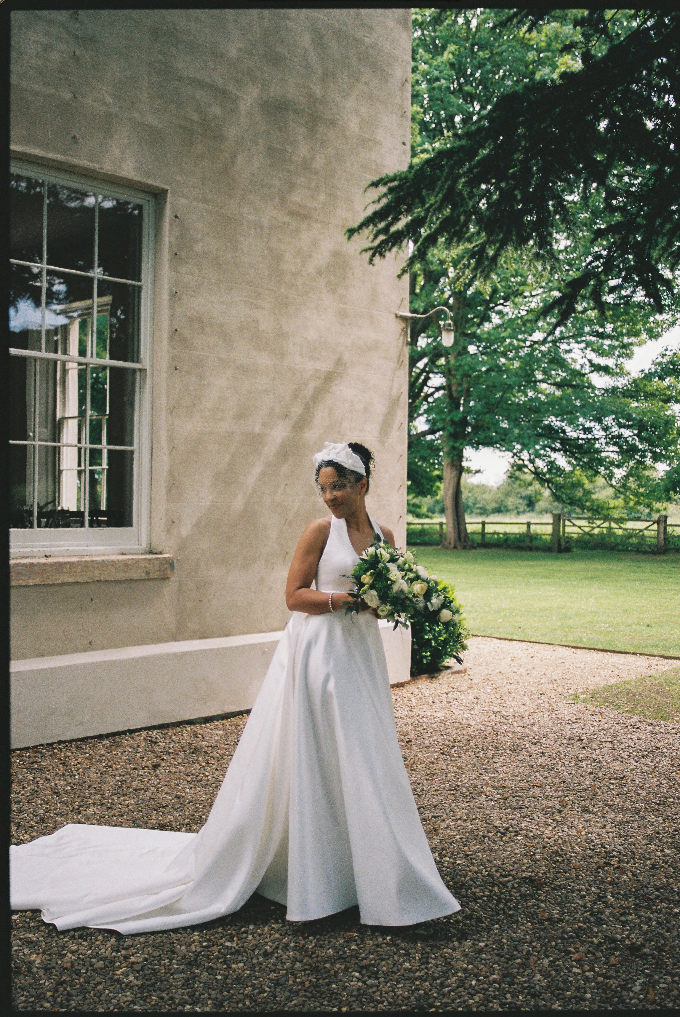 Bride Lauren standing outside Aswarby Rectory in Lincolnshire, wearing a structured wedding dress and net face veil.