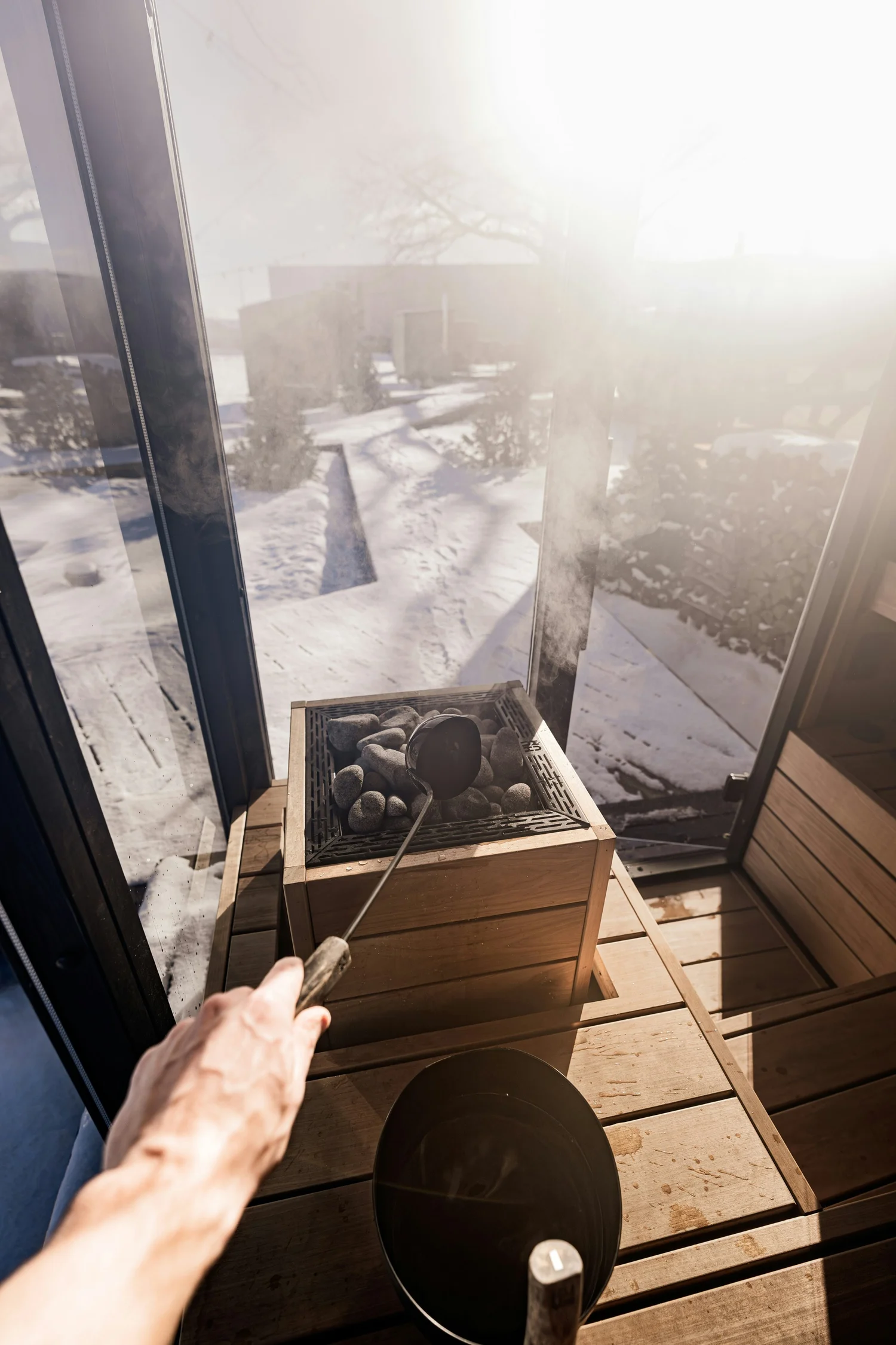 Pouring water on hot sauna stones with snow outside the window