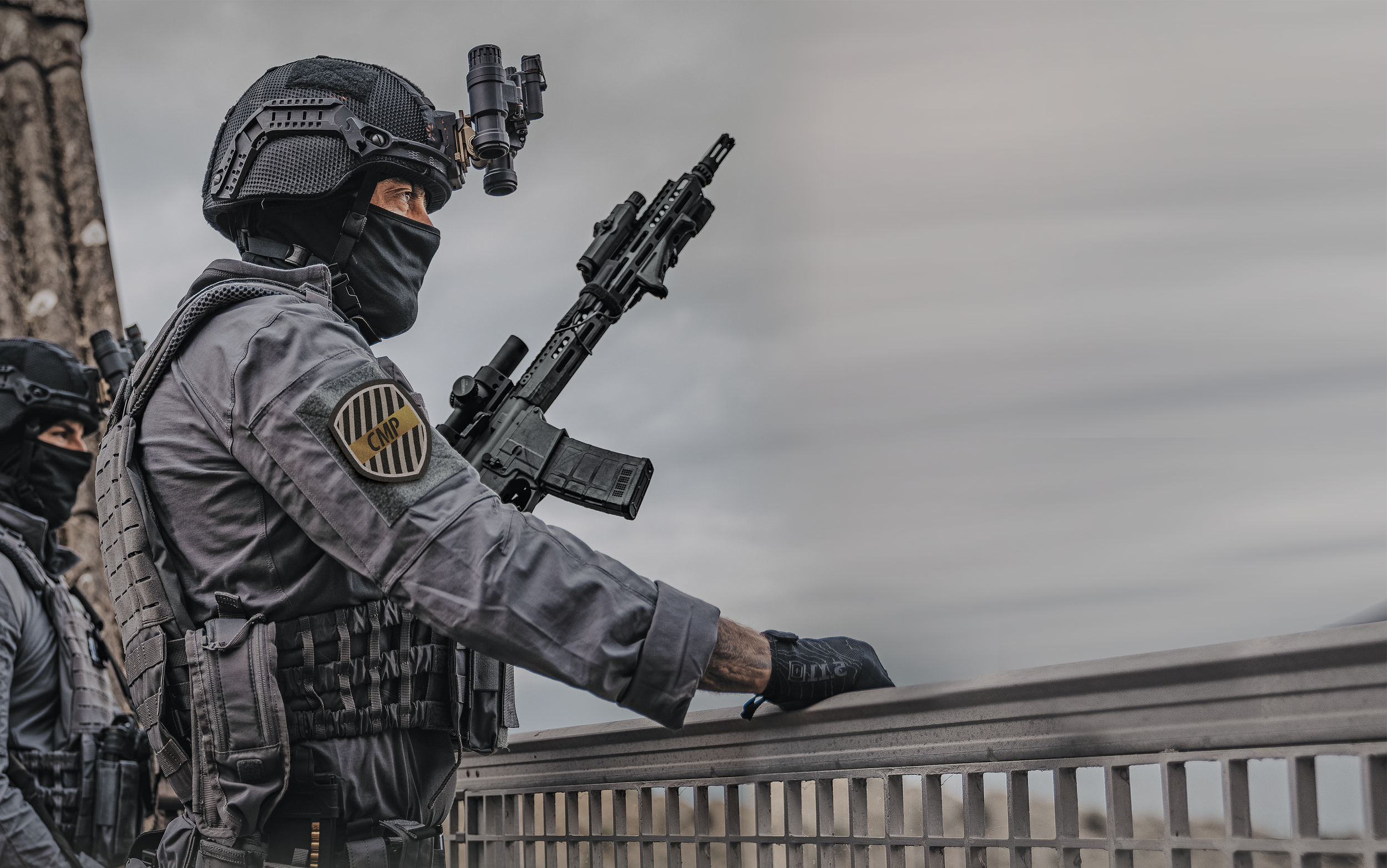 Policías antimotines con armamento y equipo táctico en un ambiente gris y nublado.