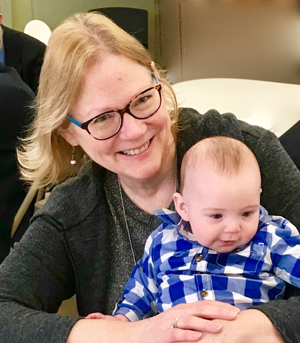Sally, with shoulder length ginger hair is holding her young grandson.