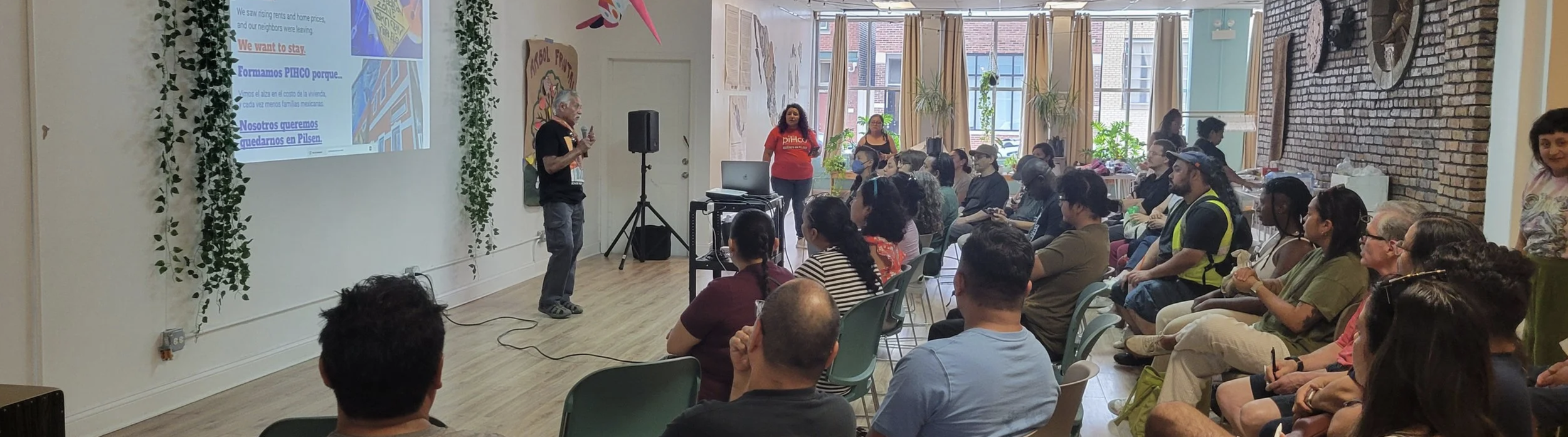 an older man with a mustache stands before a crowd of chicago residents, discussing the formation of a housing cooperative.