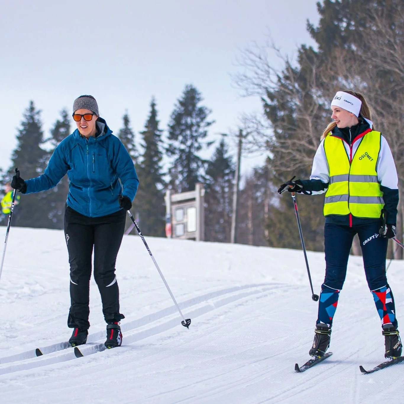 Instructor follows woman in blue jacket downhill