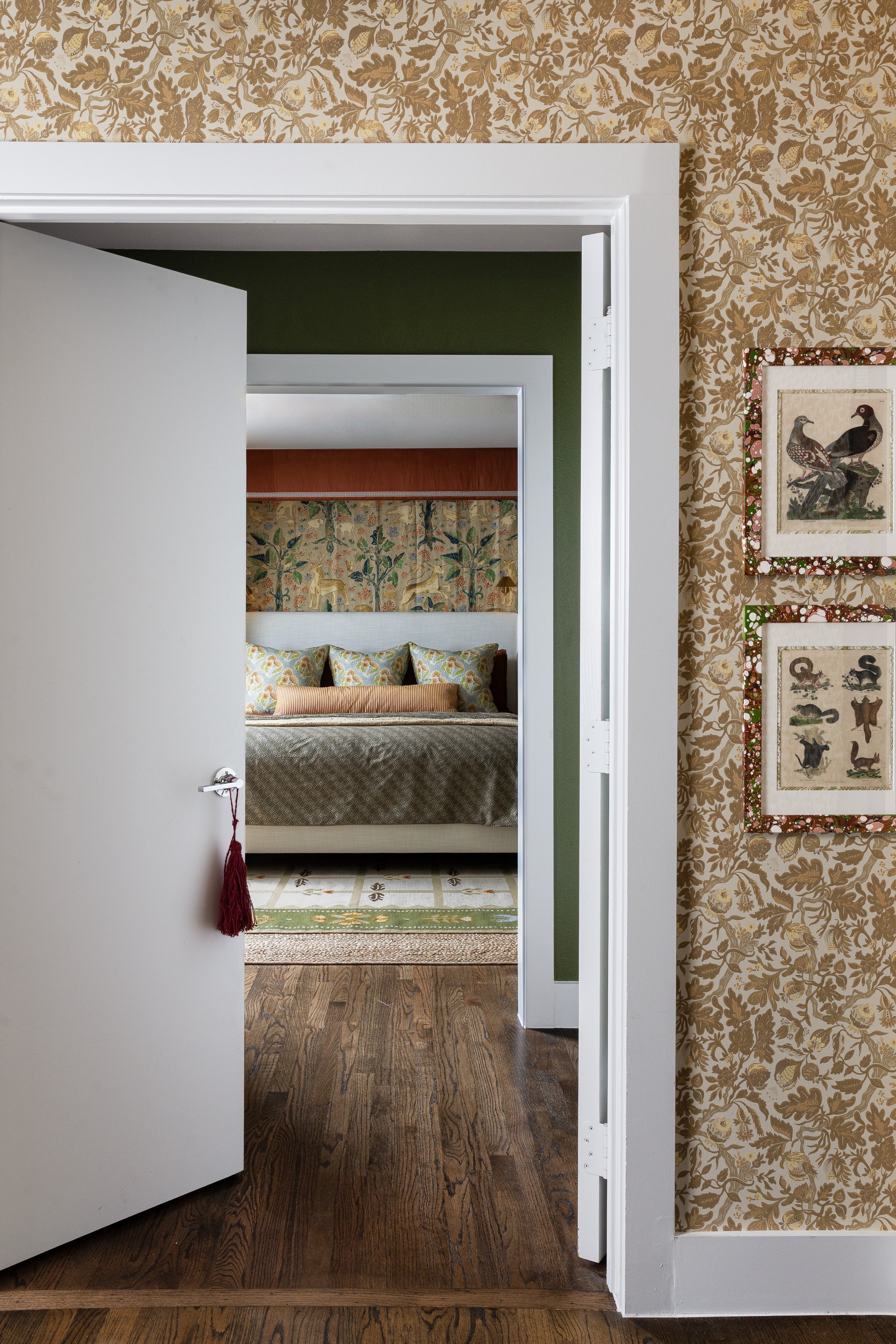 A hallway papered in gold botanical print leads into the forest green primary bedroom - one of many moments in this Dallas cottage interior where French and French used surface detail to create depth and anticipation between spaces.