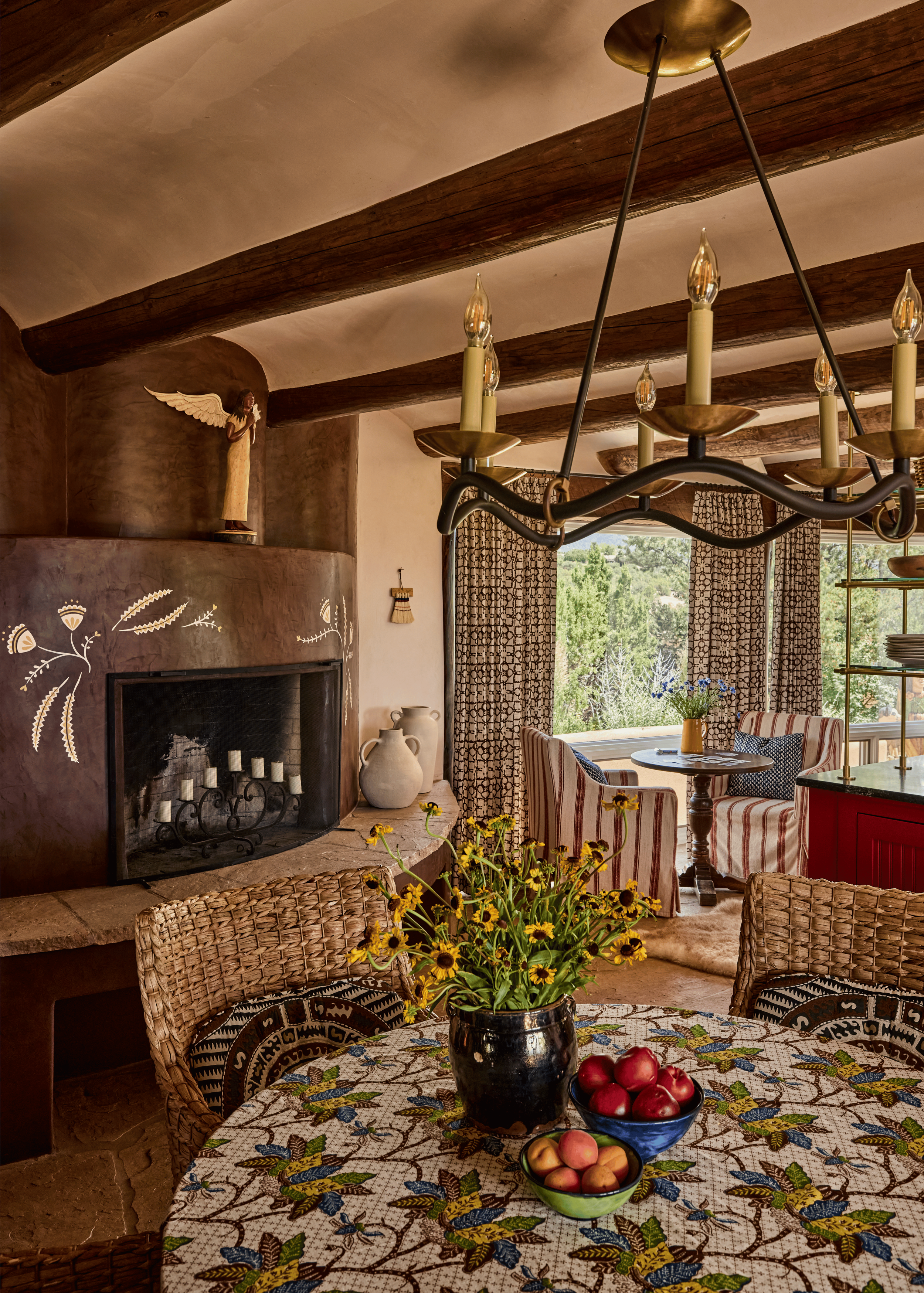 The dining room at the Mesa Project centers on a painted kiva fireplace decorated with folk-art wheat motifs and topped with a carved angel figure - a deeply personal touch that sets the tone for how French & French Interiors approaches Southwest des