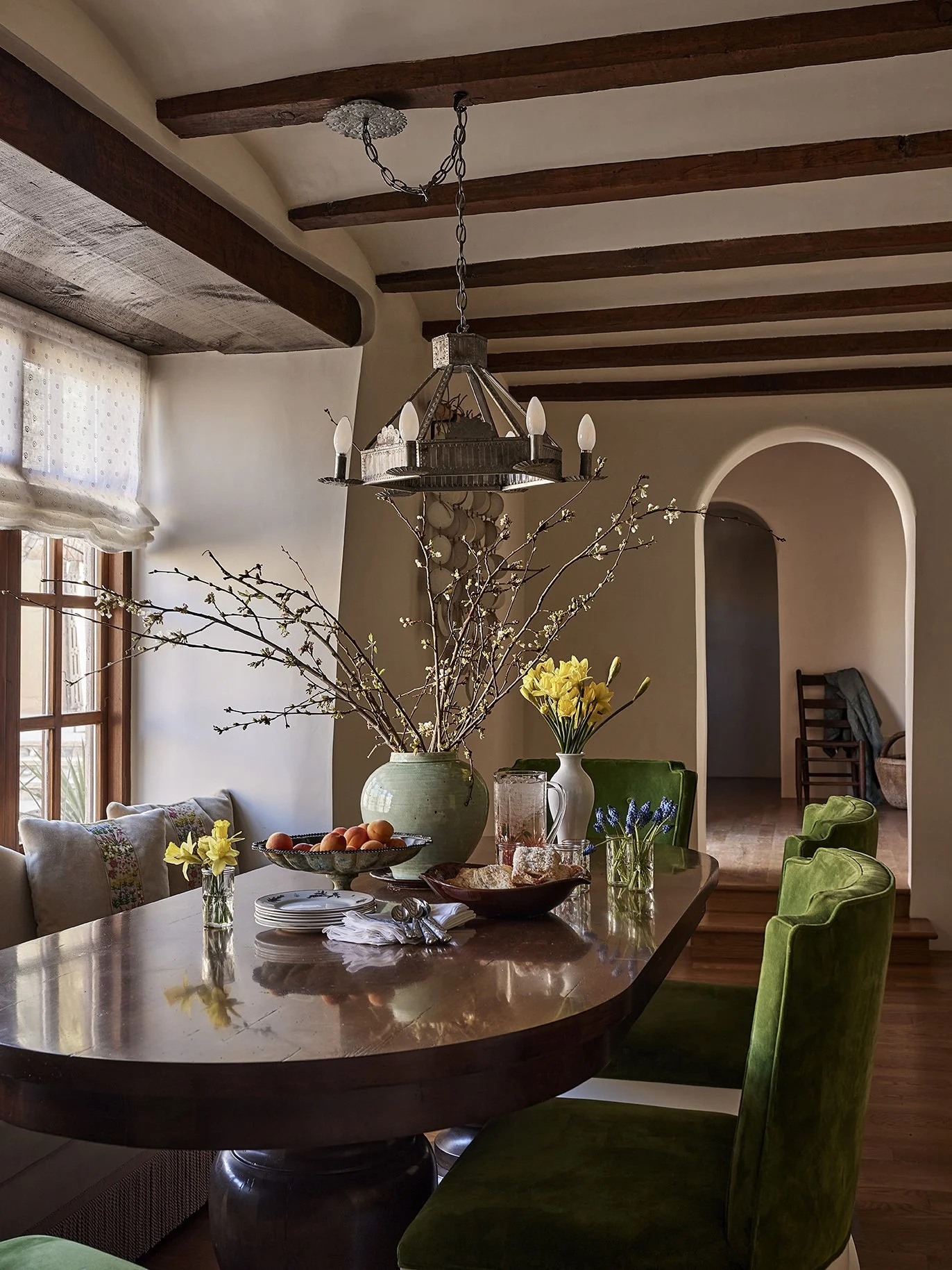 A close-up of the dining table styled with green velvet chairs, fresh flowers, and natural textures, capturing the warm New Mexican aesthetic.
