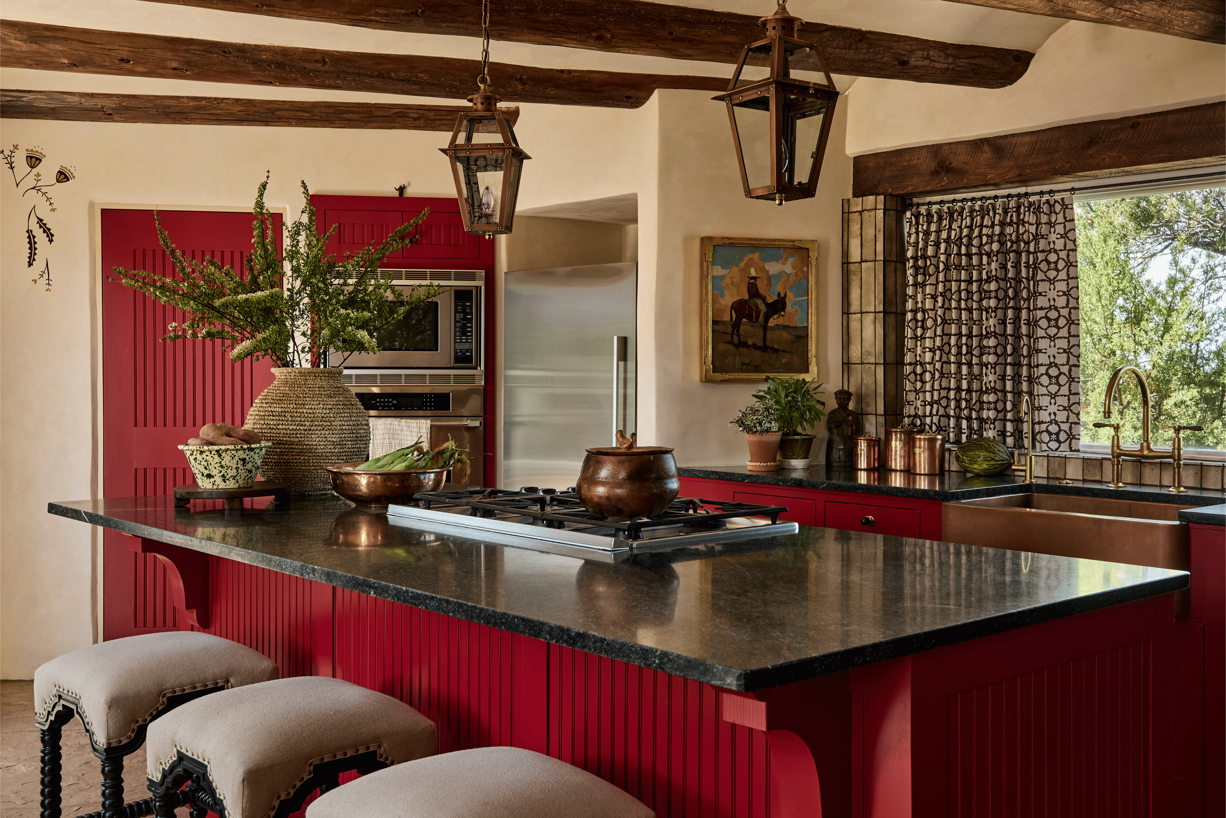 The full kitchen island at the Mesa Project - deep red beadboard, soapstone counters, and a pair of spool-leg upholstered stools set against flagstone floors and a kilim runner. This is the kitchen French & French Interiors built for a family that co