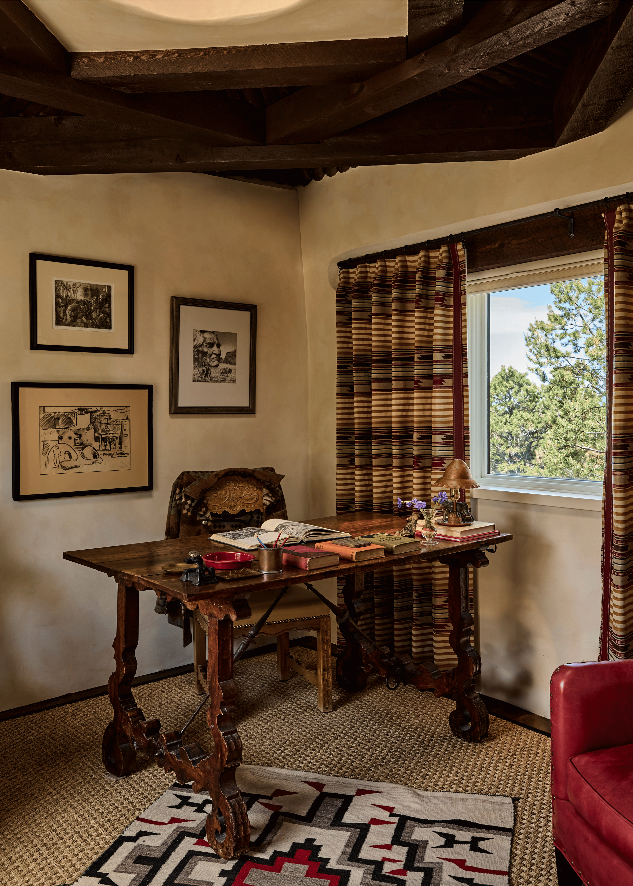 The Mesa Project's study is built around a carved Spanish trestle desk, a gallery of black and white prints on the wall, and Southwest-stripe drapes filtering high desert light. French & French Interiors designed this room as a working retreat - a sp