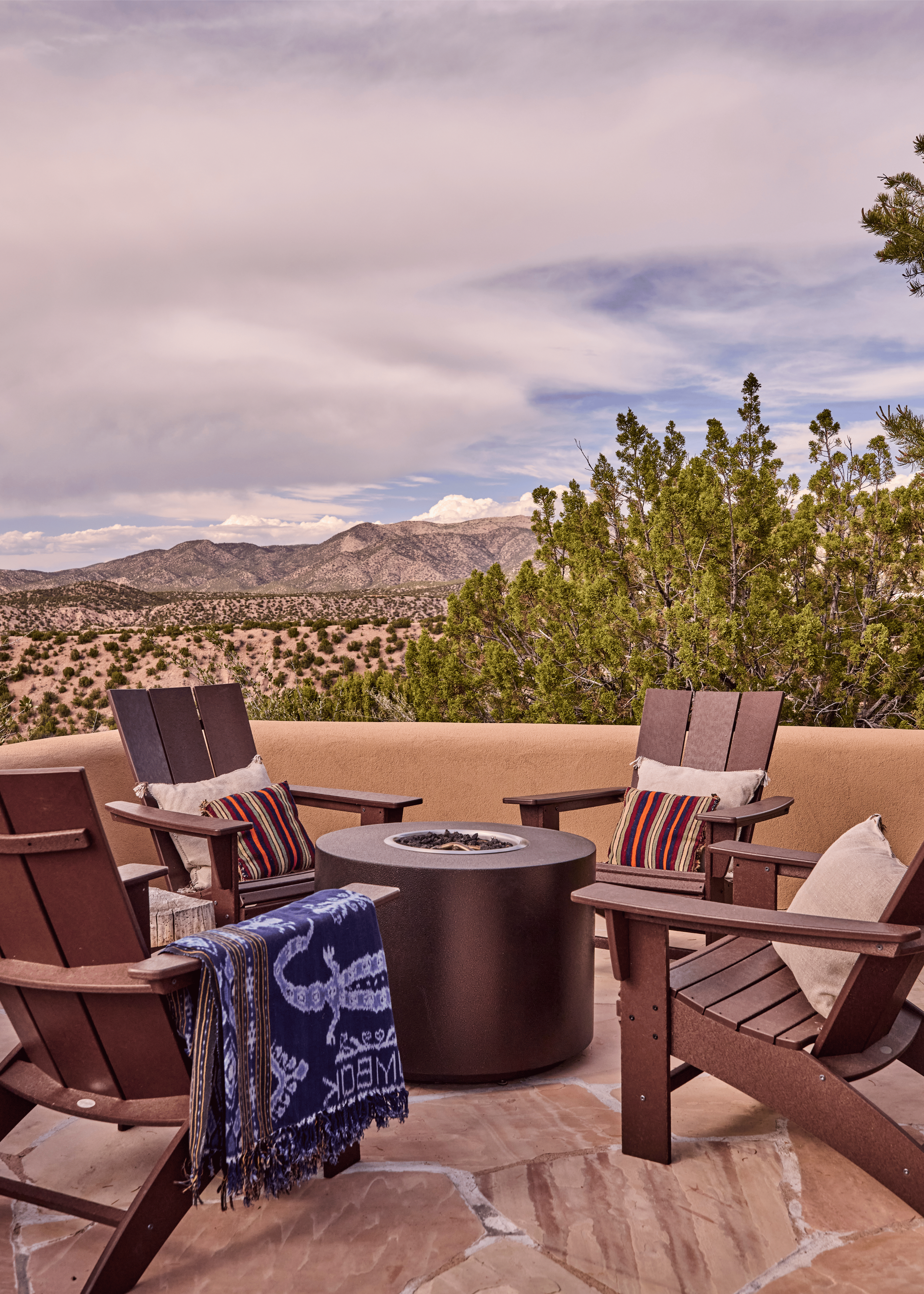 A fire pit terrace with Adirondack chairs and a full panoramic view of the Sangre de Cristo Mountains - the Mesa Project's outdoor living spaces were designed by French & French Interiors to be as intentional as every room inside, making full use of 