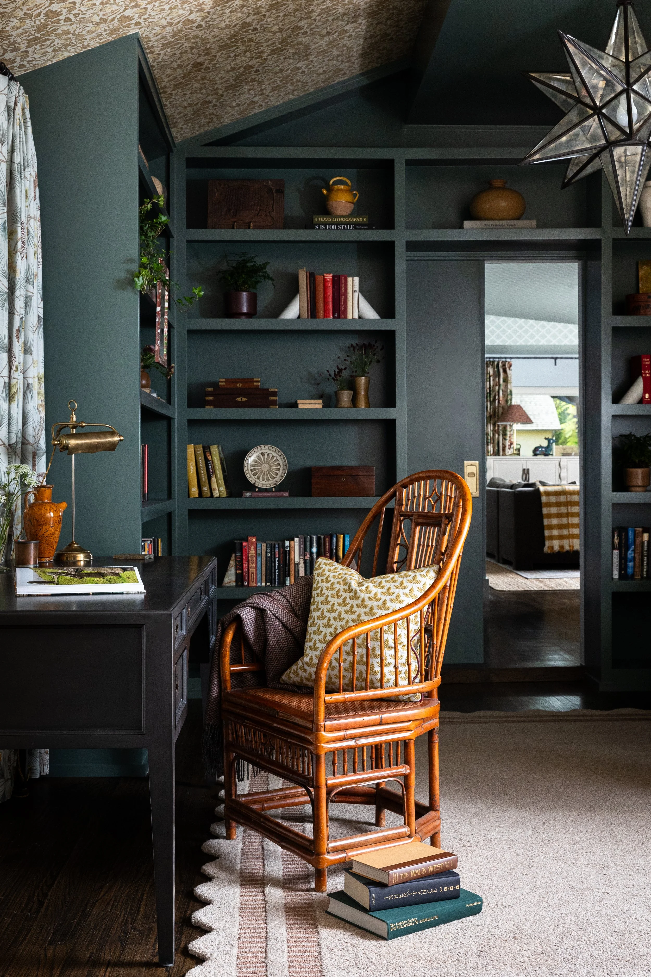 Floor-to-ceiling built-ins in deep teal hold a curated collection of books, pottery, and found objects in the study of this Dallas cottage home - a room that rewards attention, designed by French and French Interiors for a Dallas family.