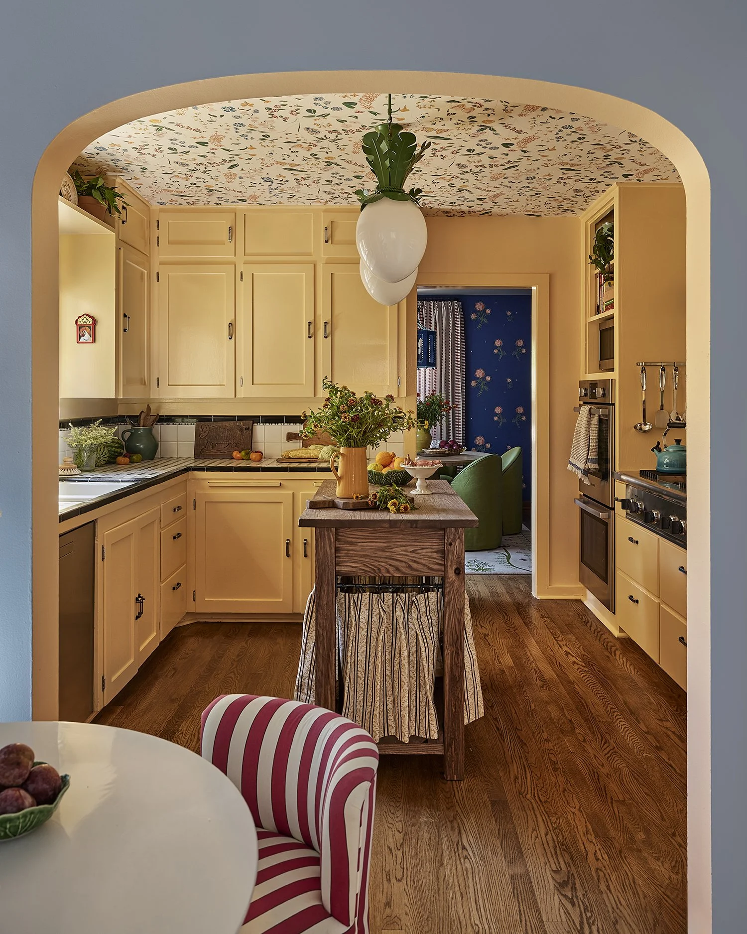 Eclectic kitchen blending vintage charm and floral detail, leading to a blue dining room in this modern Santa Fe adobe home.